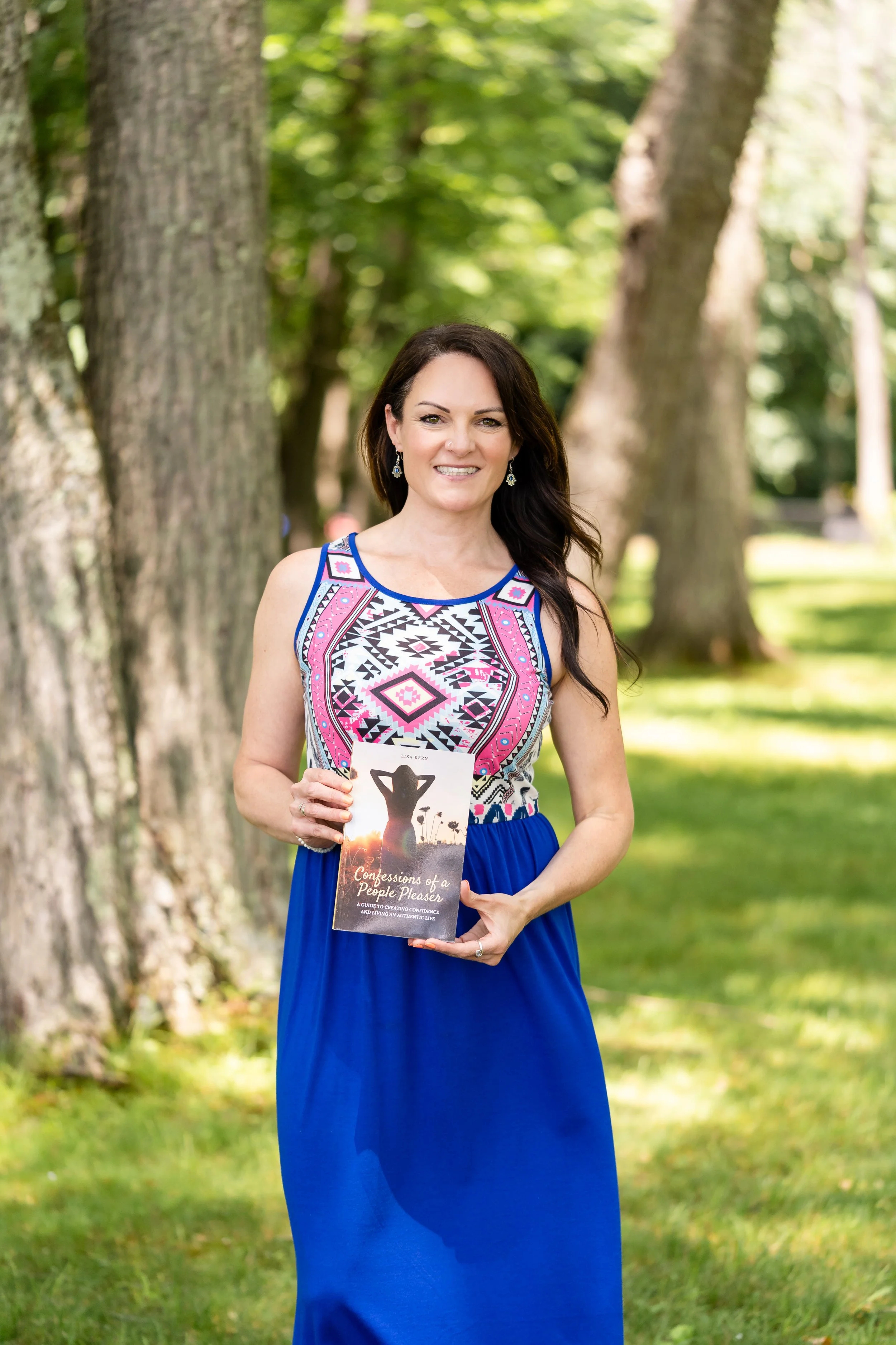 Lisa Kern, author of Confessions of a People Pleaser, holding her book outdoors