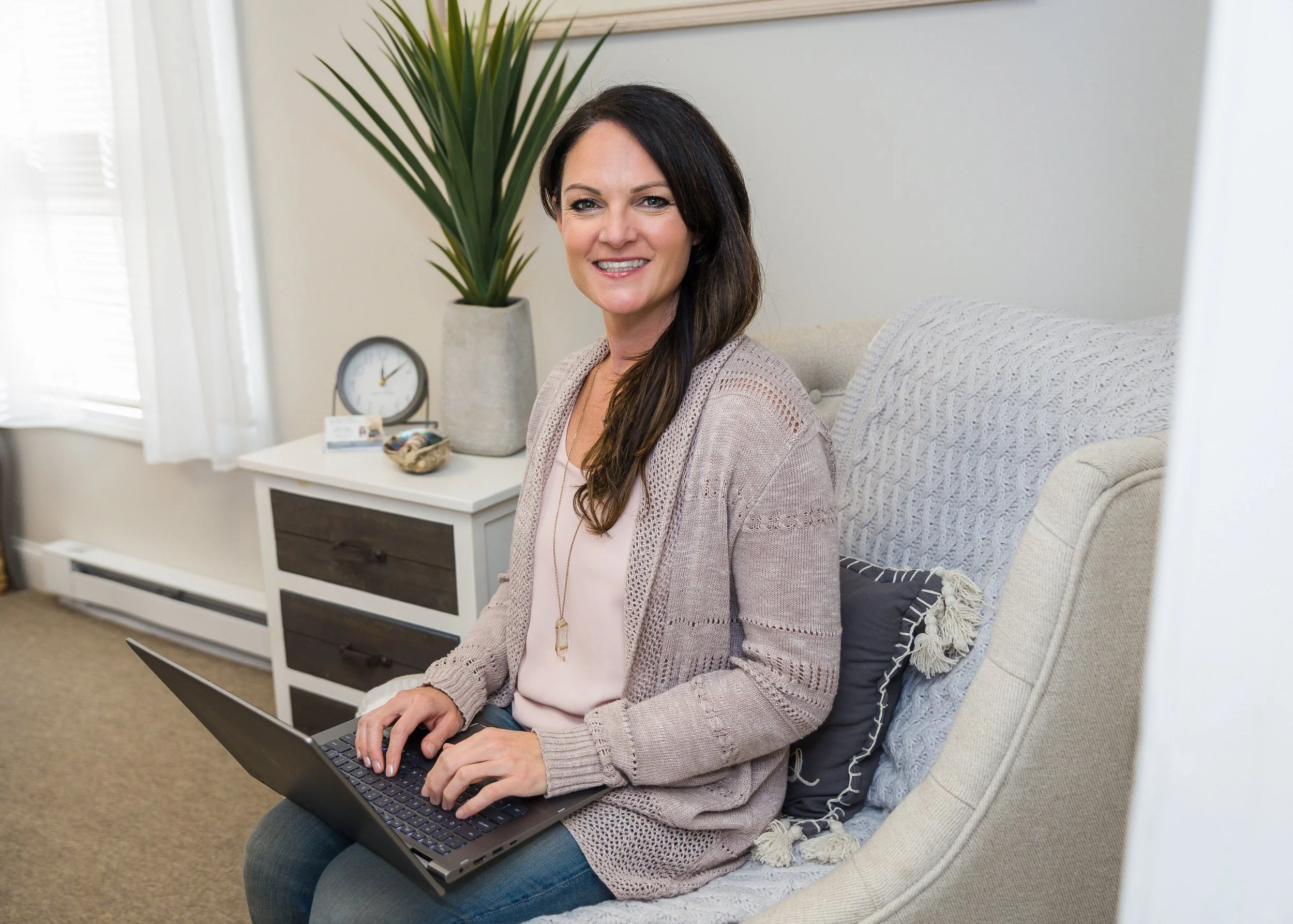 Lisa Kern, Reiki Master and holistic therapist, smiling while working on a laptop during a coaching session