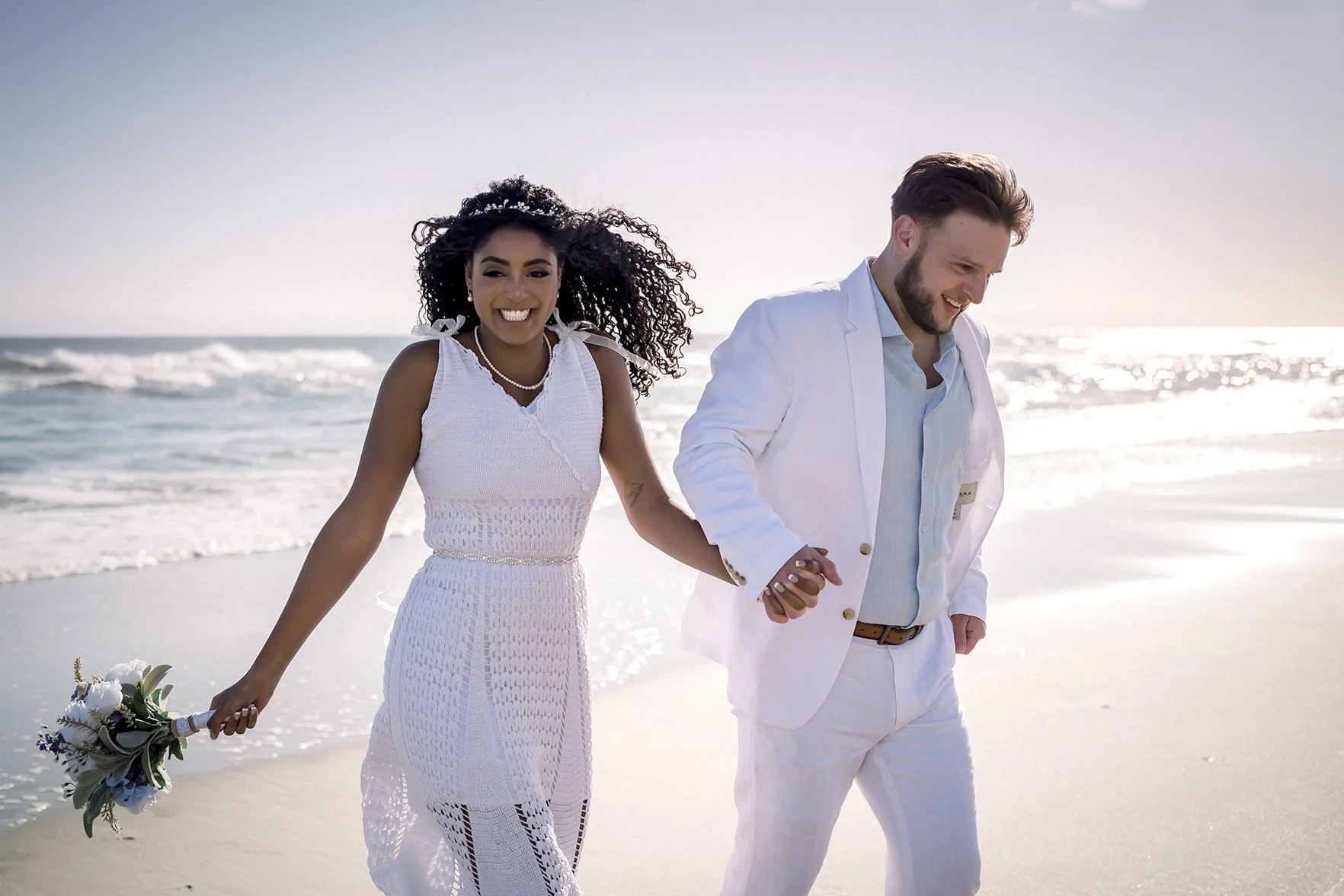 happy couple running out of the ocean after their beach wedding ceremony