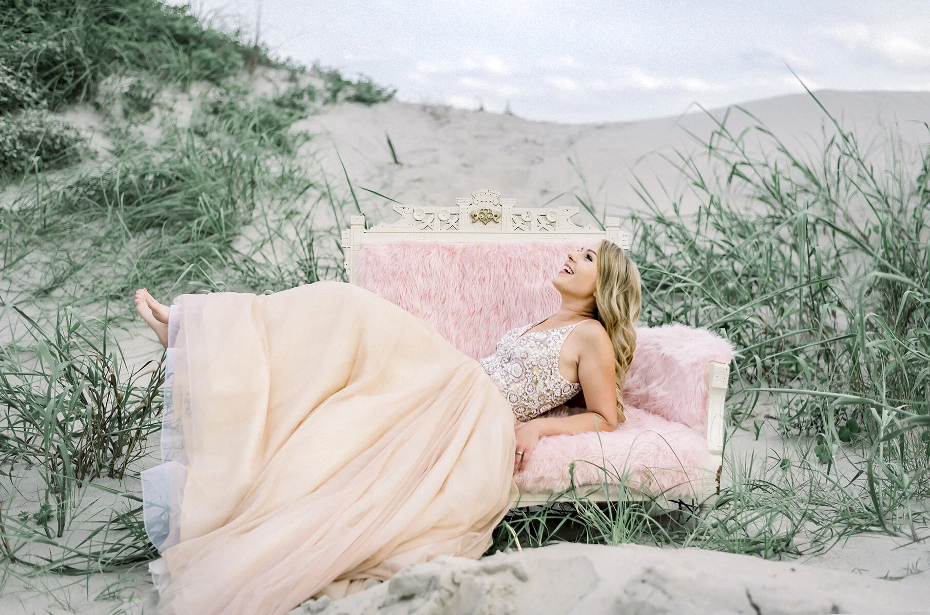 Barefoot beach bride lounging on a settee in the sand in Surf City NC