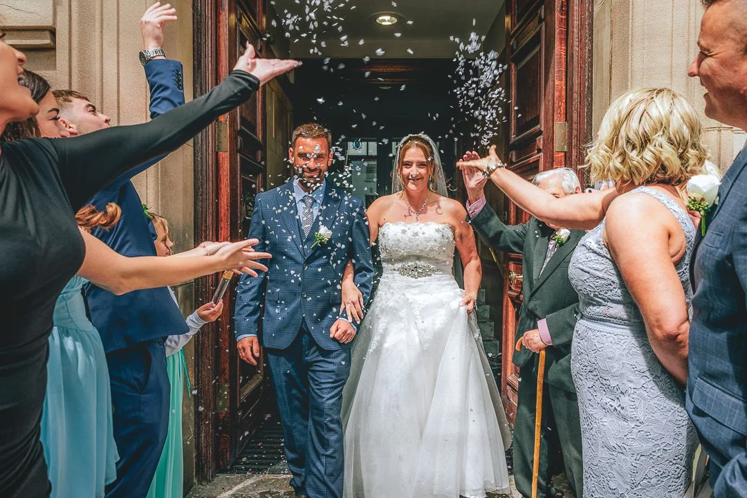 Rachel and Matt are greeted by confetti and cheers following their wedding at Sale Town Hall in Greater Manchester