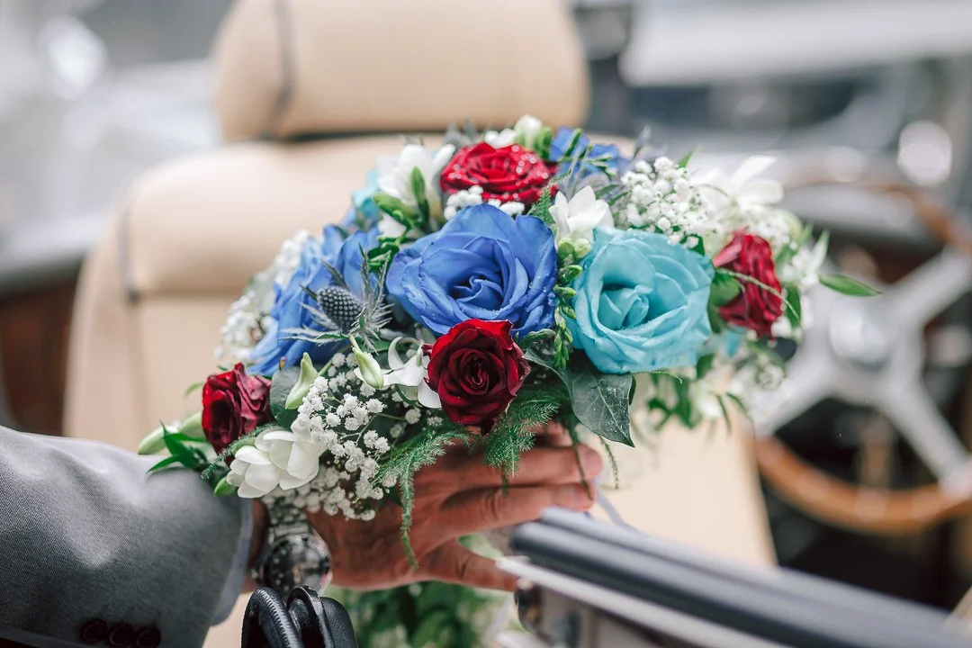 Blue and red floral bouquet with white mini flowers and lush green details