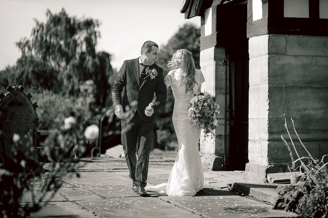 Groom and bride walk from Saint Martins Church hand in hand following their wedding ceremony in Sale, Greater Manchester