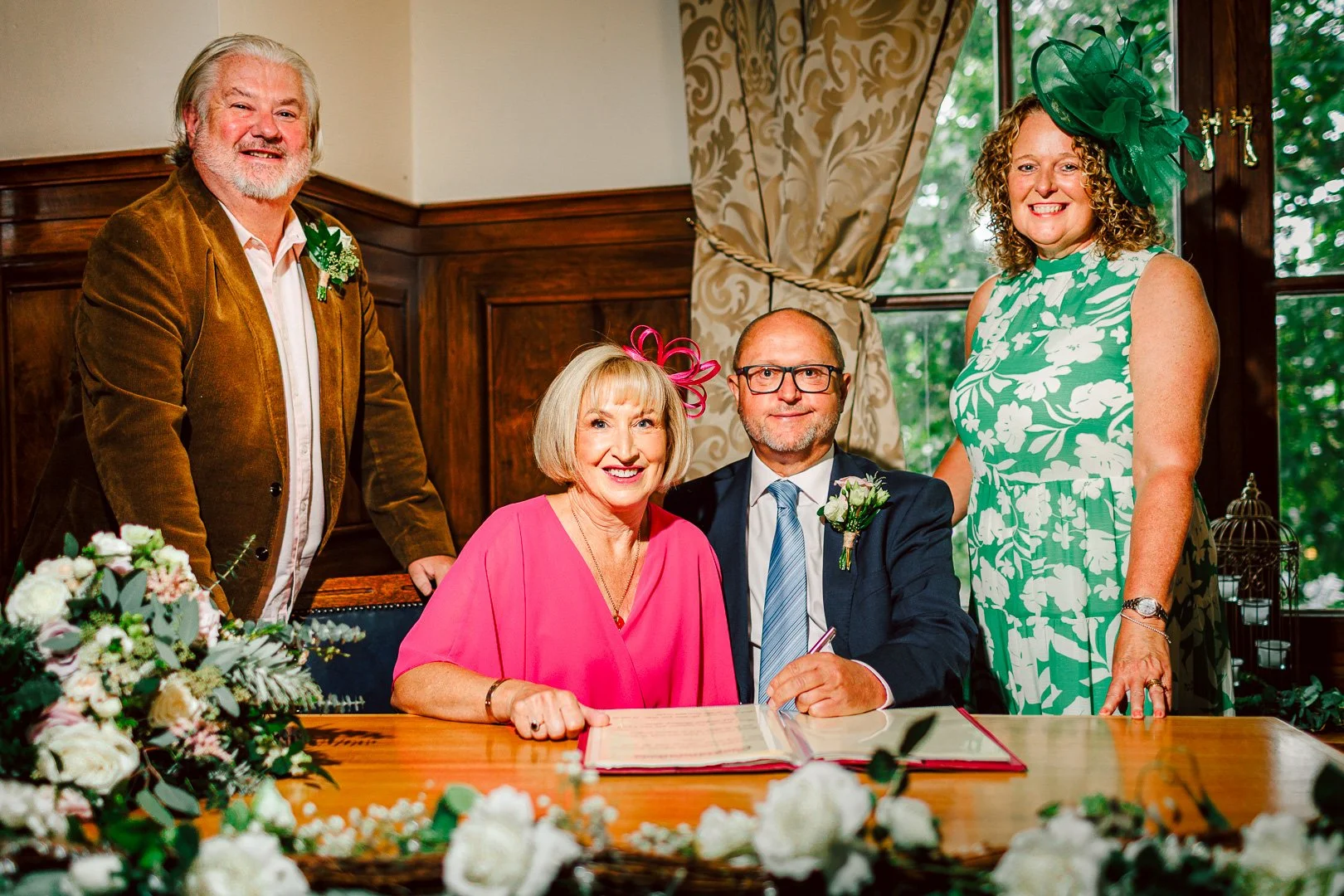 Newlyweds signing the marriage register on a wooden desk with their witnesses, documented by a wedding photographer at Sale Town Hall.
