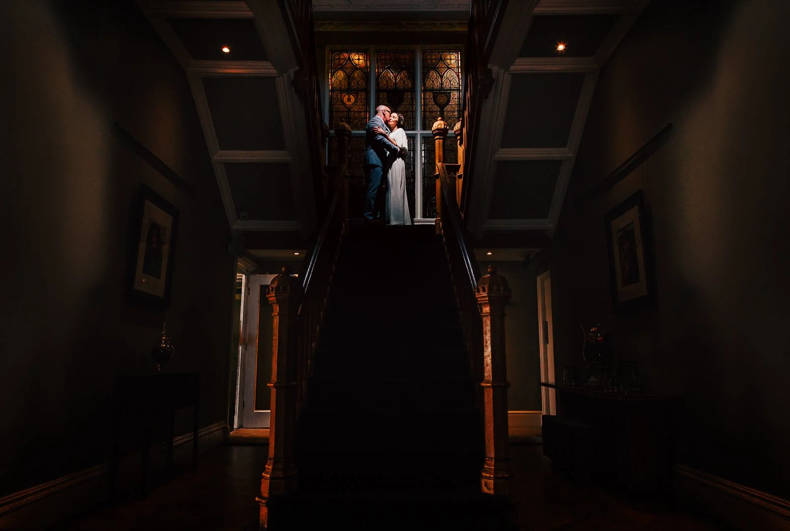 bride and groom Alison and Dave share an embrace at the top of the main staircase in didsbury House Hotel on their wedding day
