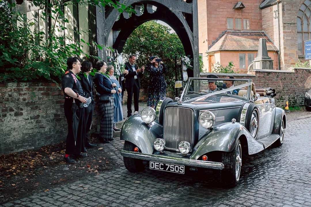 Silver open top Jaguar takes newlyweds from Saint Martins Church following their wedding ceremony