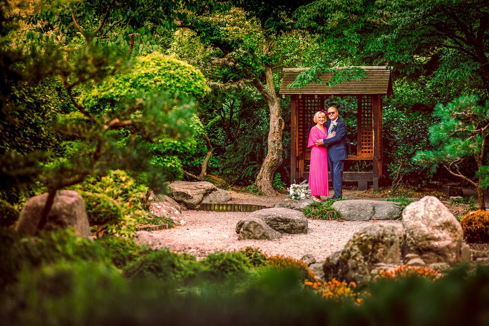 Bride and groom posing together in Walkden Gardens in Sale, a lush green outdoor portrait by a local Sale Town Hall wedding photographer.