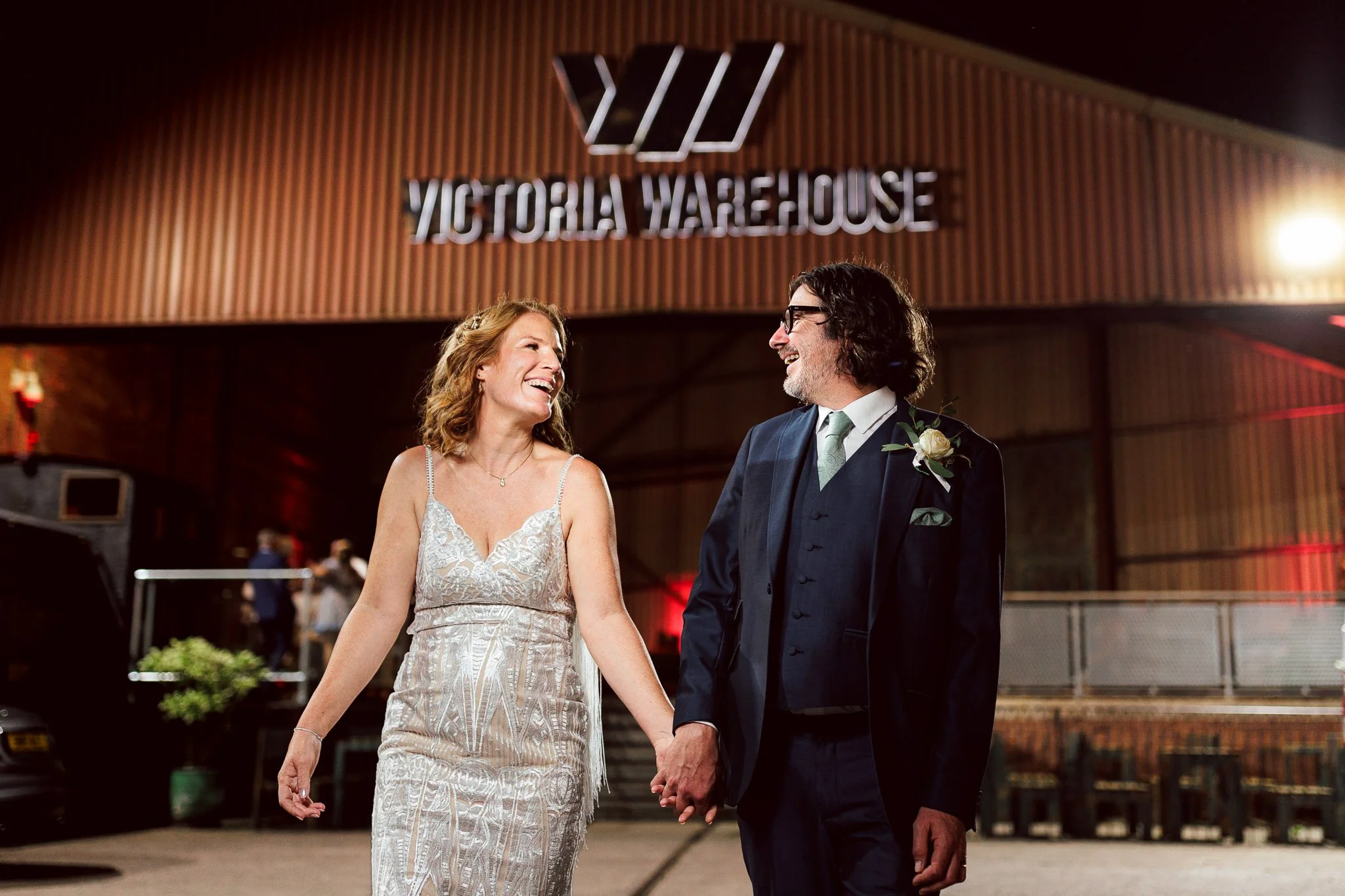 Bride and goom walk away from Victoria Warehouse hand in hand on their wedding day in Manchester