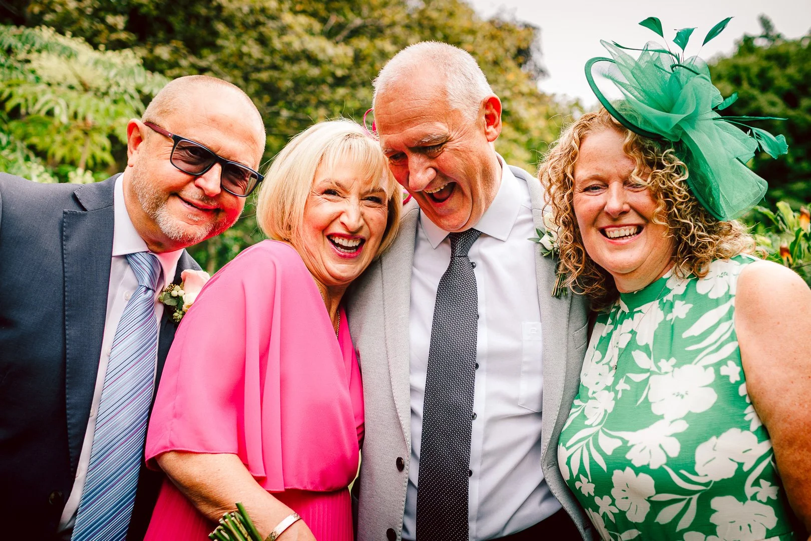 Close-up candid shot of the bride, groom, and close friends laughing together, taken by a wedding photographer in Walkden Gardens following their wedding at Sale Town Hall.