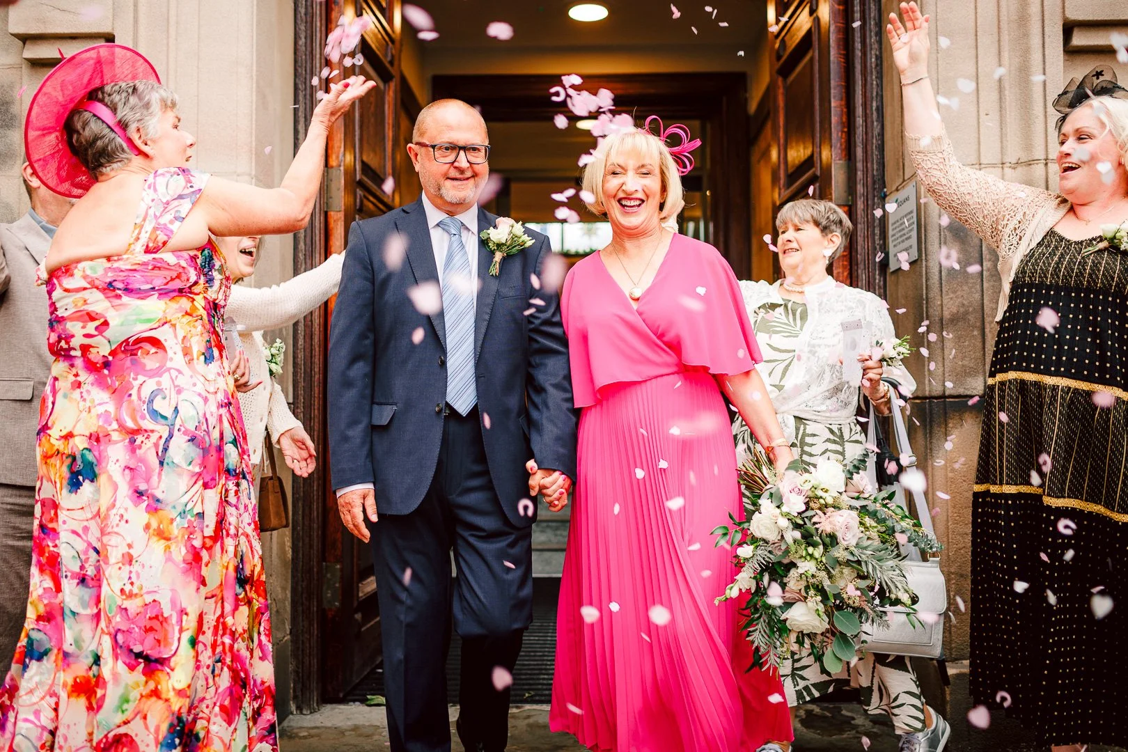 Wedding guests throwing confetti over the newly married couple outside the doors, shot by a wedding photographer at Sale Town Hall.