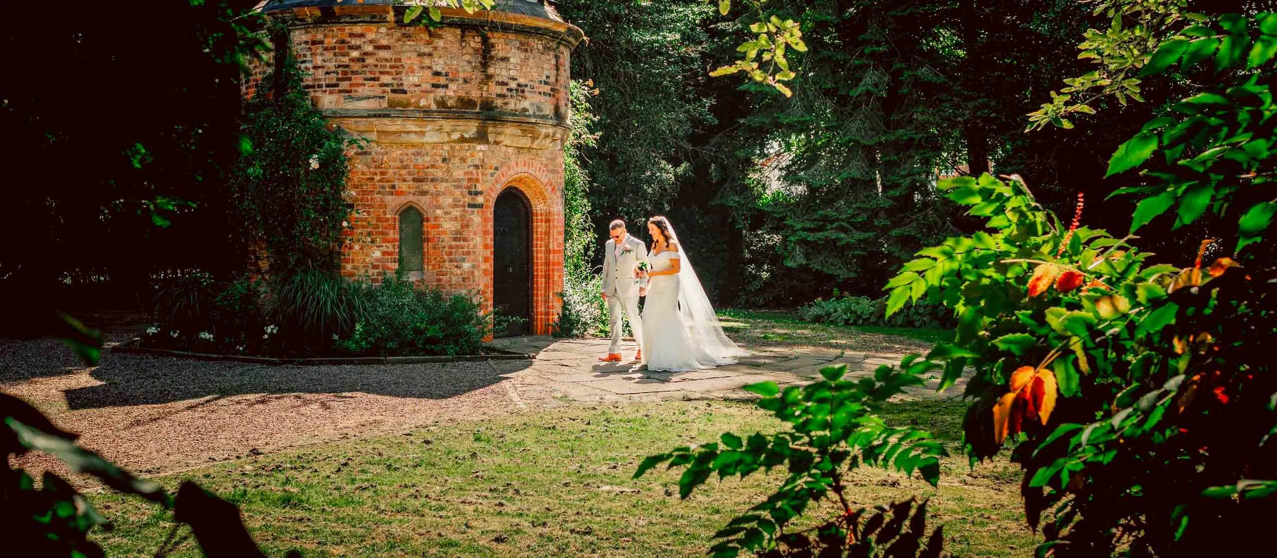 Bride and groom posing in Walkden Gardens, Sale, captured by a Manchester wedding photographer.