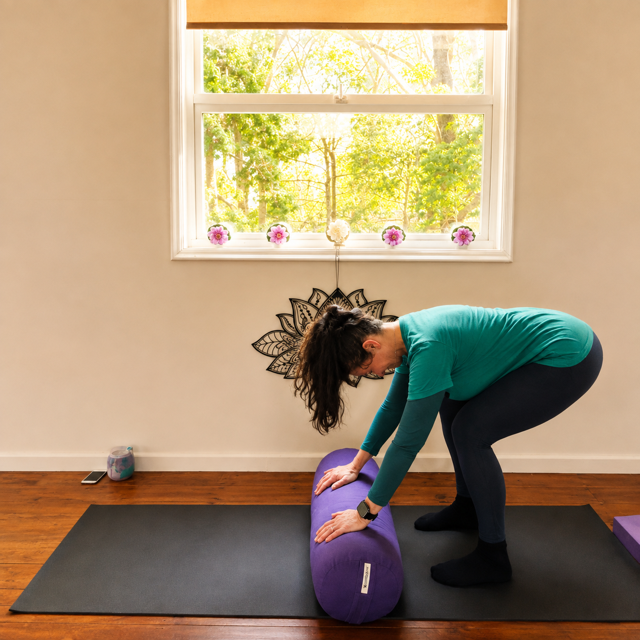 Jodie teaching a gentle forward bend with yoga bolster