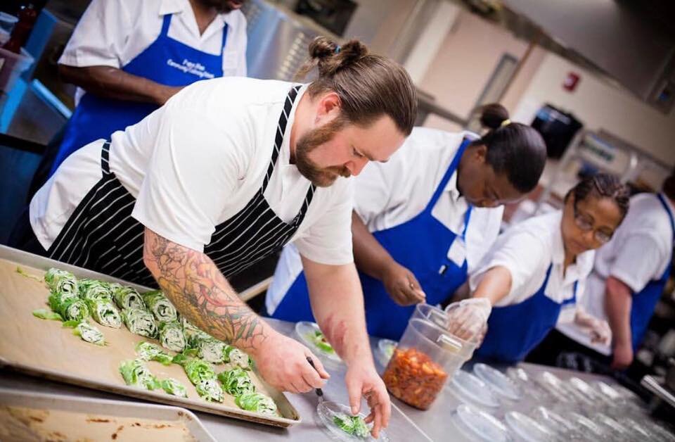  Chef Tobin works with students in the CC Pearce Culinary School, plating meals at a Community Dinner. 