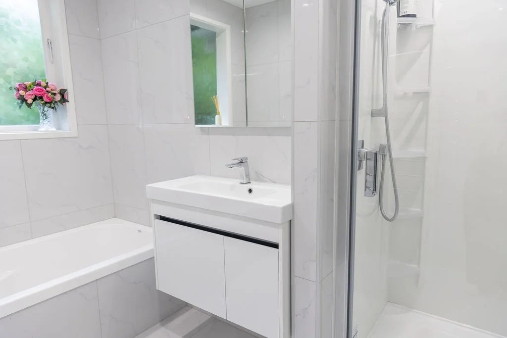 Modern bathroom with a white bathtub, a vanity with a sink, a mirror, and a glass shower enclosure.