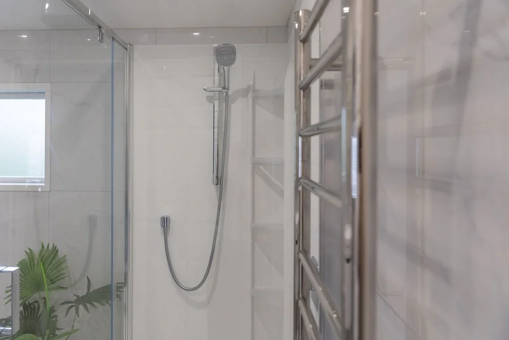 Shower area with a handheld showerhead and a glass door in a modern bathroom.