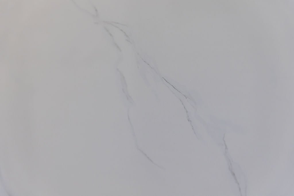 Close-up view of a white marble surface with gray veining.