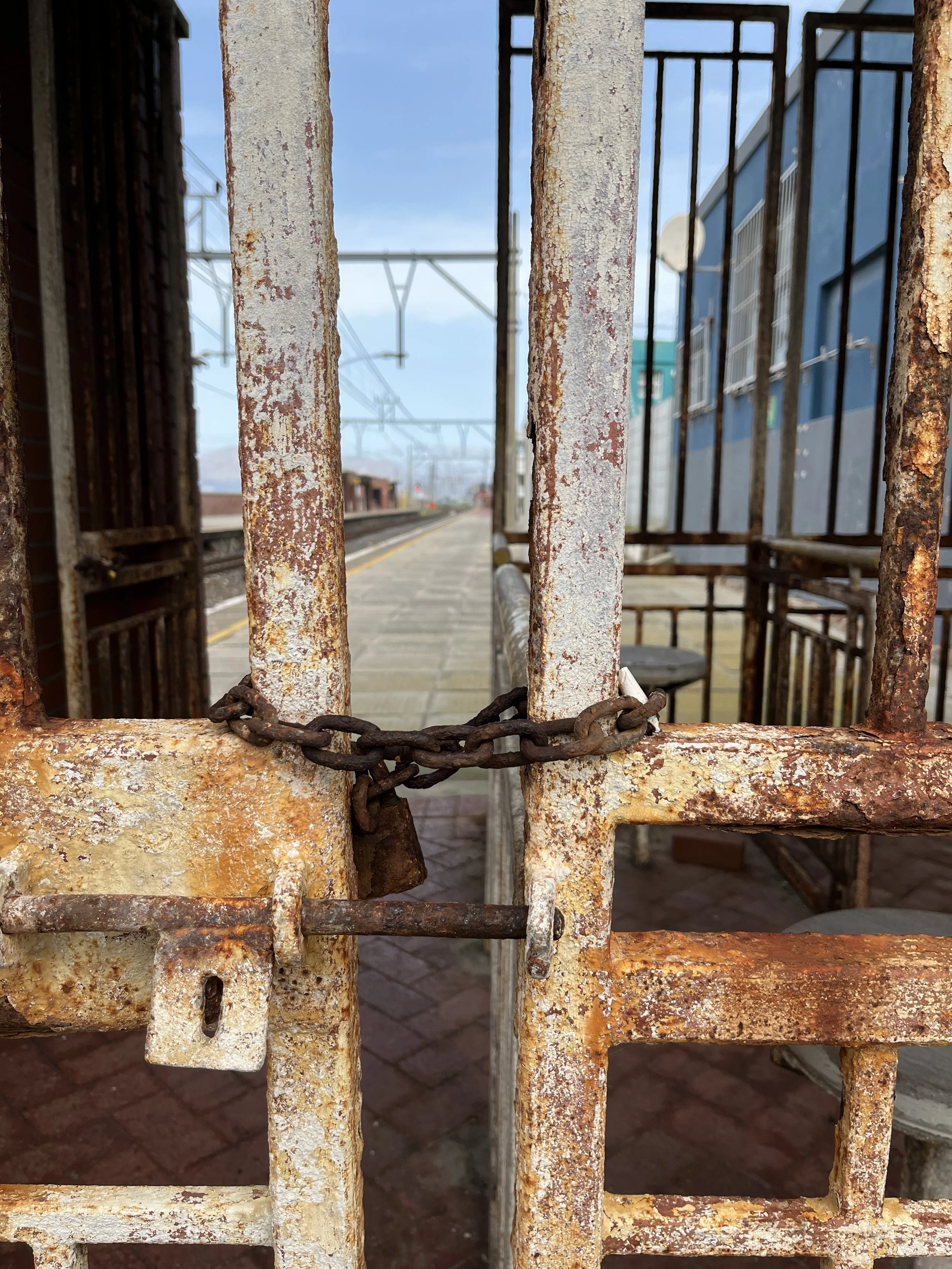 Cold metal chains hang across the entrance of the station. Locked gates. No way in. No ticket in hand. Defeat whispers, but hope still lingers.