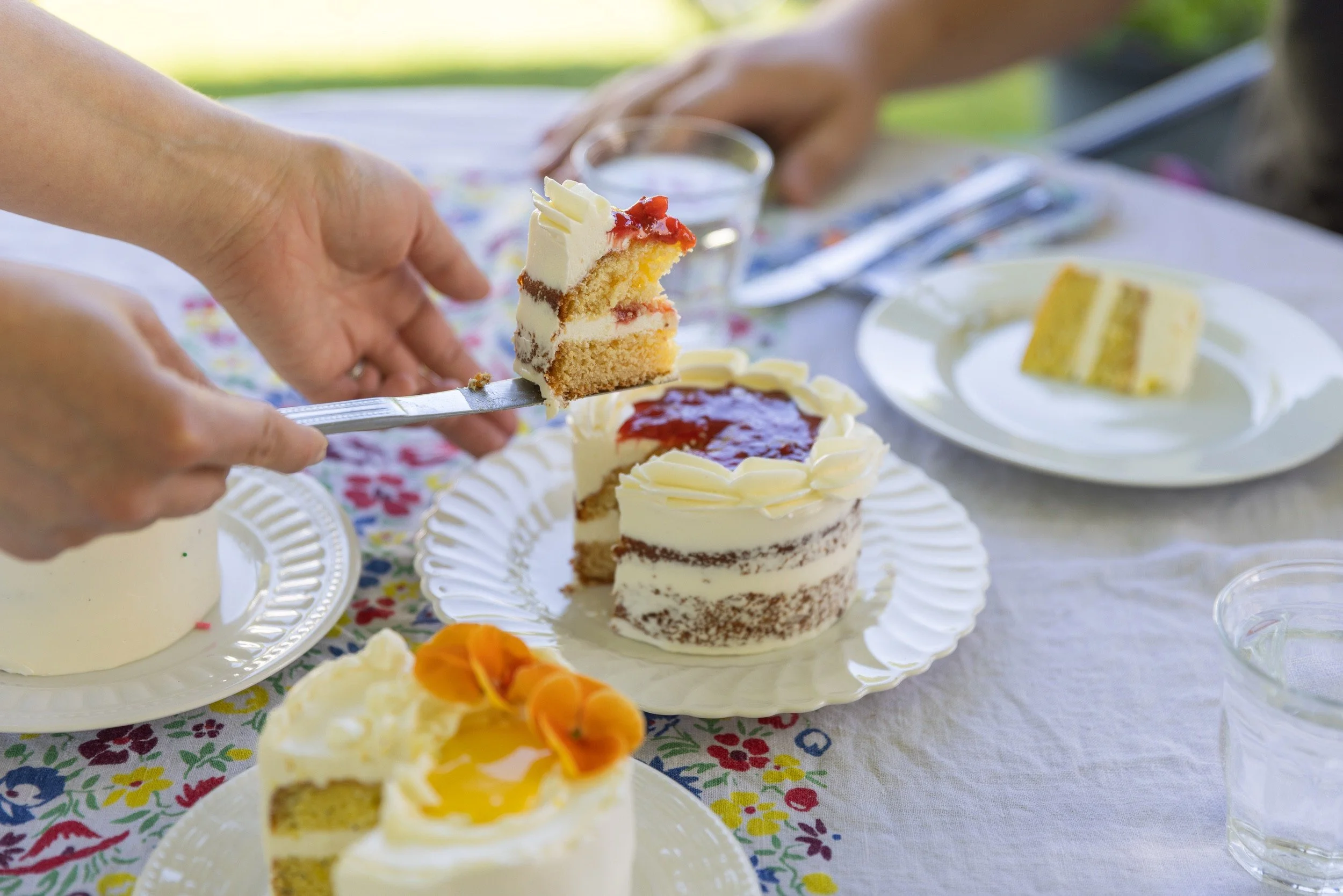 Close-up of a fork lifting a bite of naked cake topped with berry jam during a cake tasting.