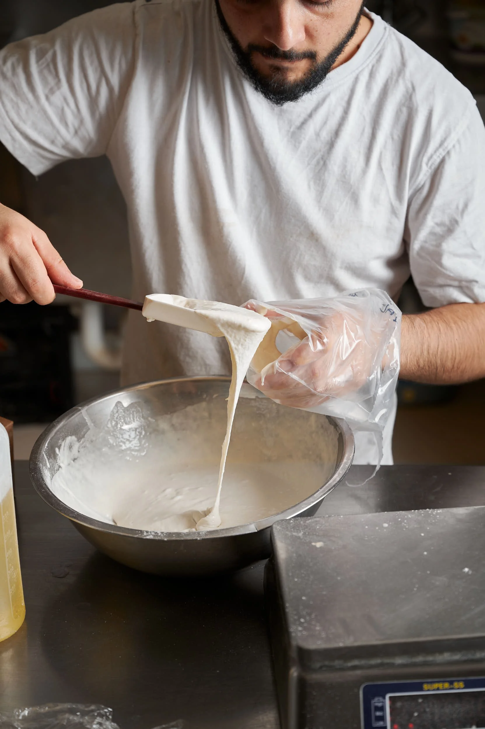Editorial food photography: baker scooping mixture into piping bag by Melbourne food photographer Charlotte Orr