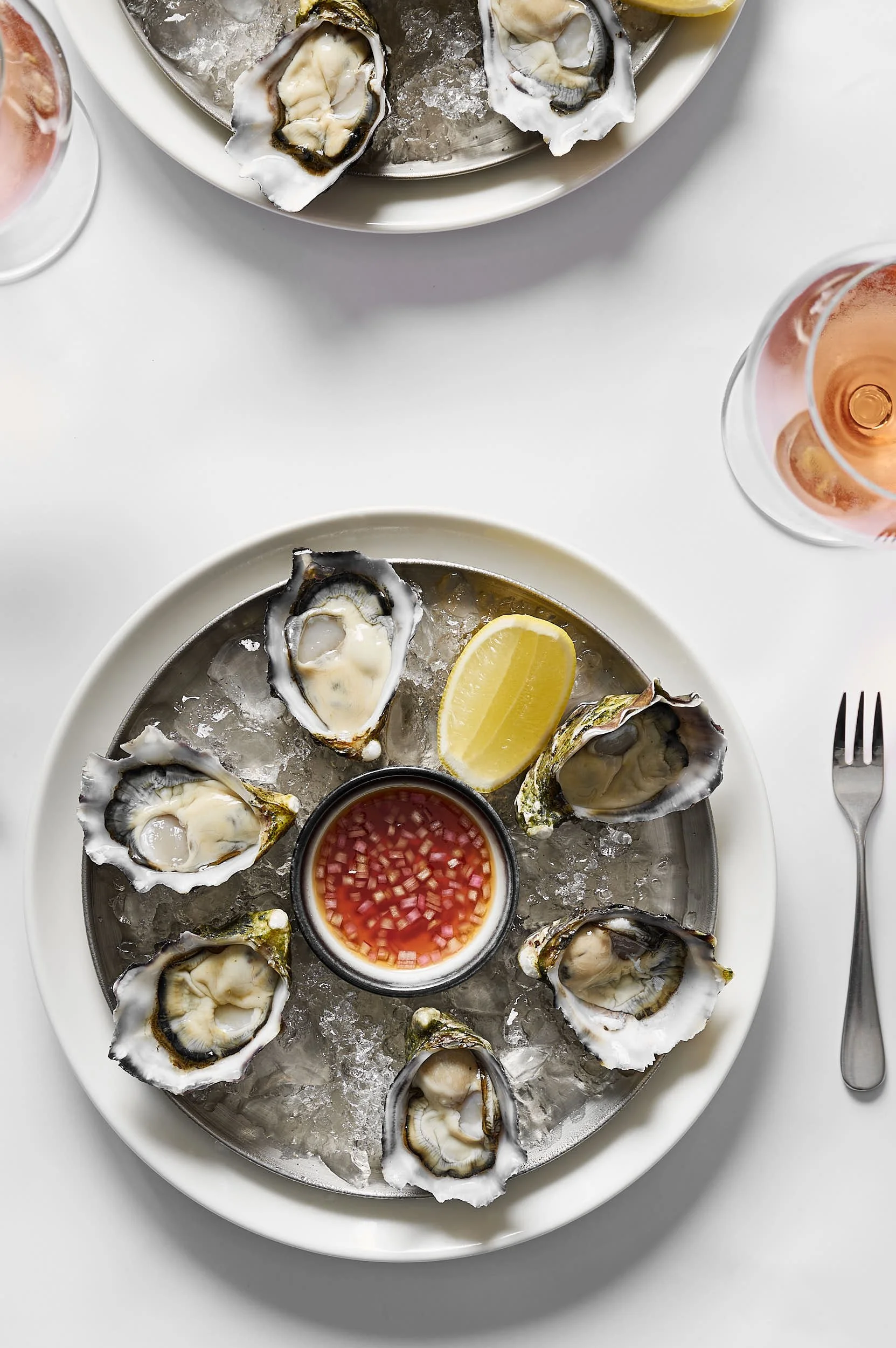 Beautiful hospitality photography: two plates of oysters with rose wine by Charlotte Orr, photographer based in Melbourne