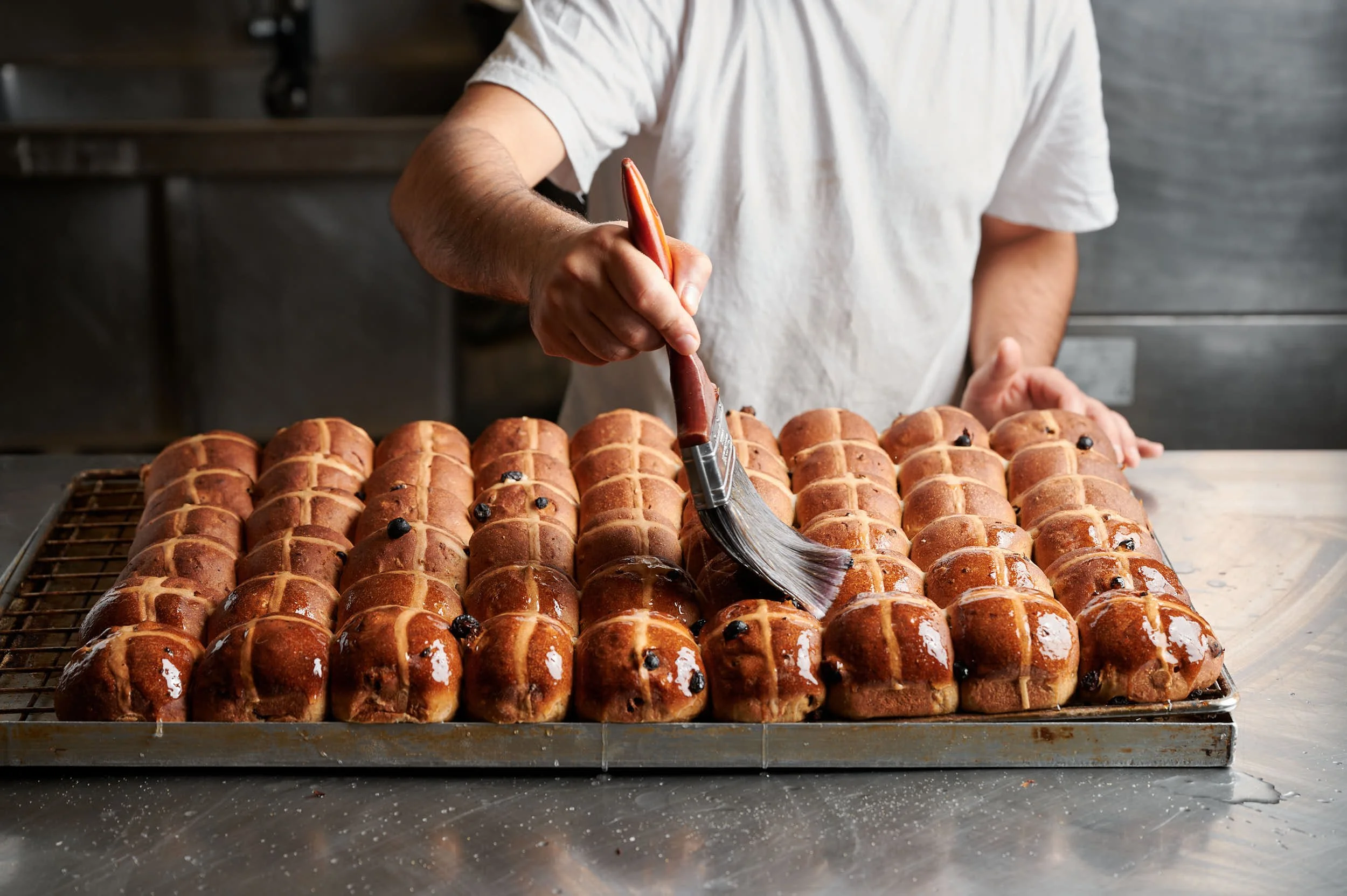 Editorial food photography: baker glazing hot cross buns by Melbourne food photographer Charlotte Orr