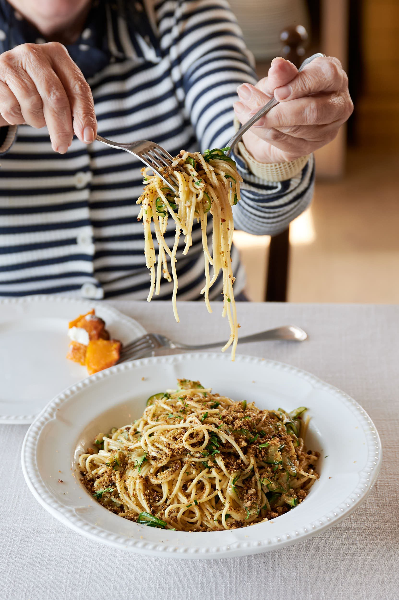 Beautiful hospitality photography: hands lifting spaghetti from shared bowl by Charlotte Orr, photographer based in Melbourne, Australia
