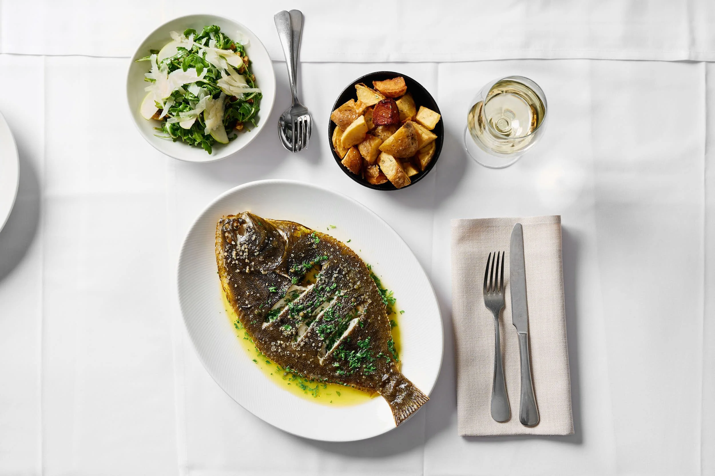 Beautiful hospitality photography: whole flounder, potatoes, salad and wine by Charlotte Orr, photographer based in Melbourne, Australia