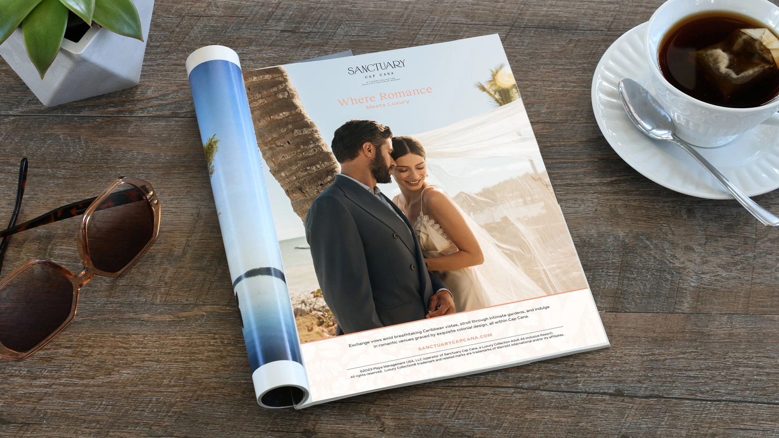 A full page magazine ad for weddings at Sanctuary Cap Cana displayed in a magazine open on a desk with a plant, sunglasses and cup of tea.