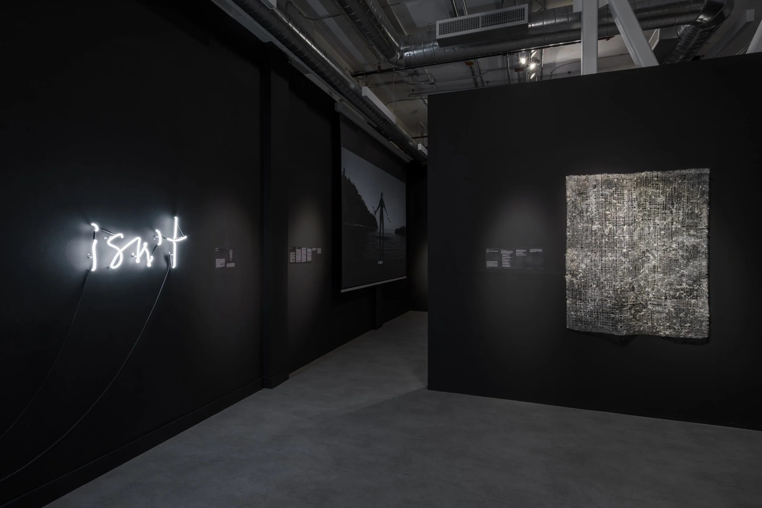  Installation view,  Vulnerable Pleasures , Gallery Gachet, Vancouver, 2025. Left: Christine D’Onofrio,  Isn’t , 2025, neon. Right: Damla Tamer,  Untitled Weaving for Living Room Window , 2025, Handwoven silver thread coated with cottonwood seeds. 