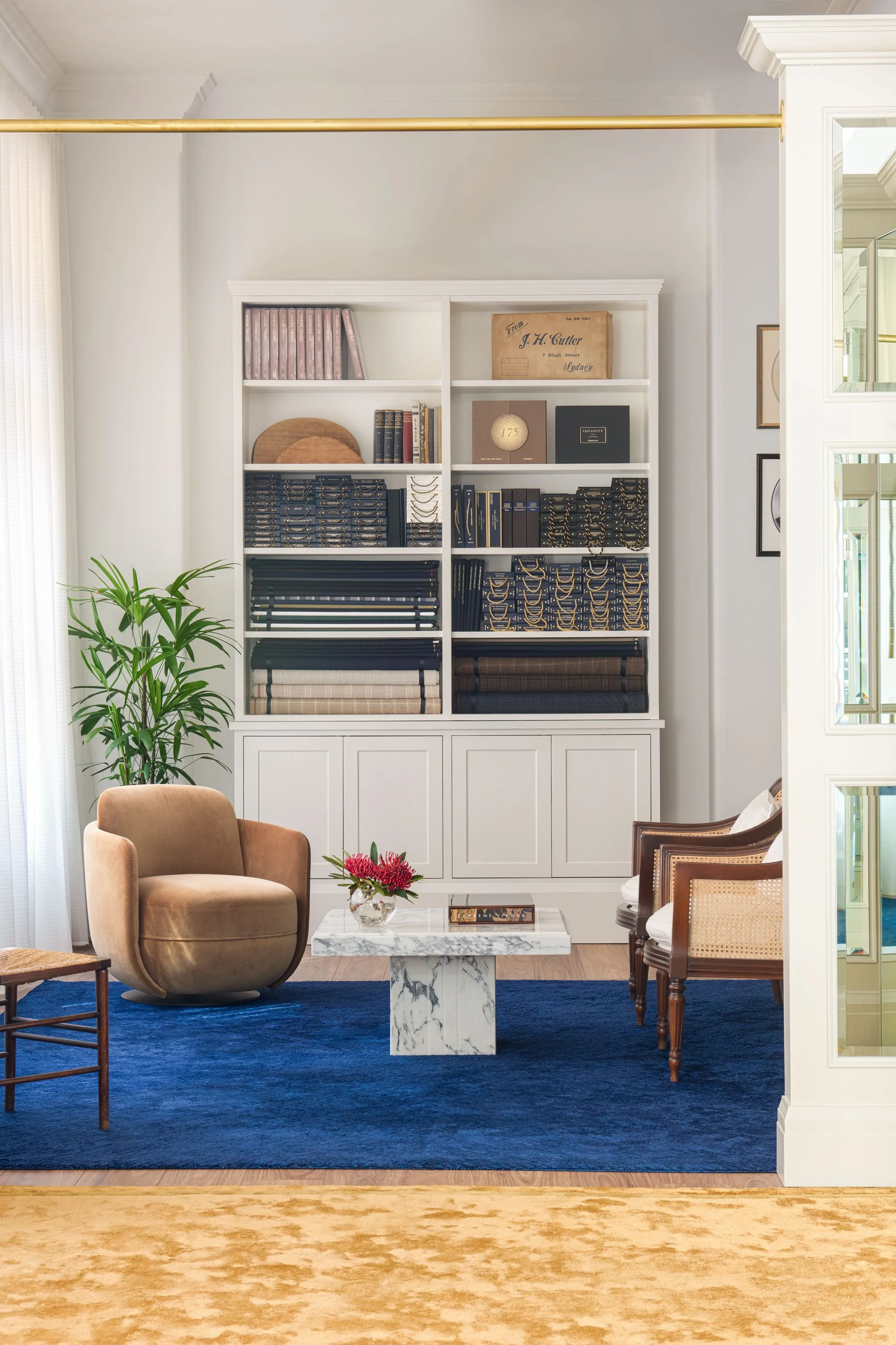 Elegant wall cabinetry featuring suiting fabrics, framed portraits and heritage tailoring elements in J.H. Cutler’s atelier by Kaiko Design.