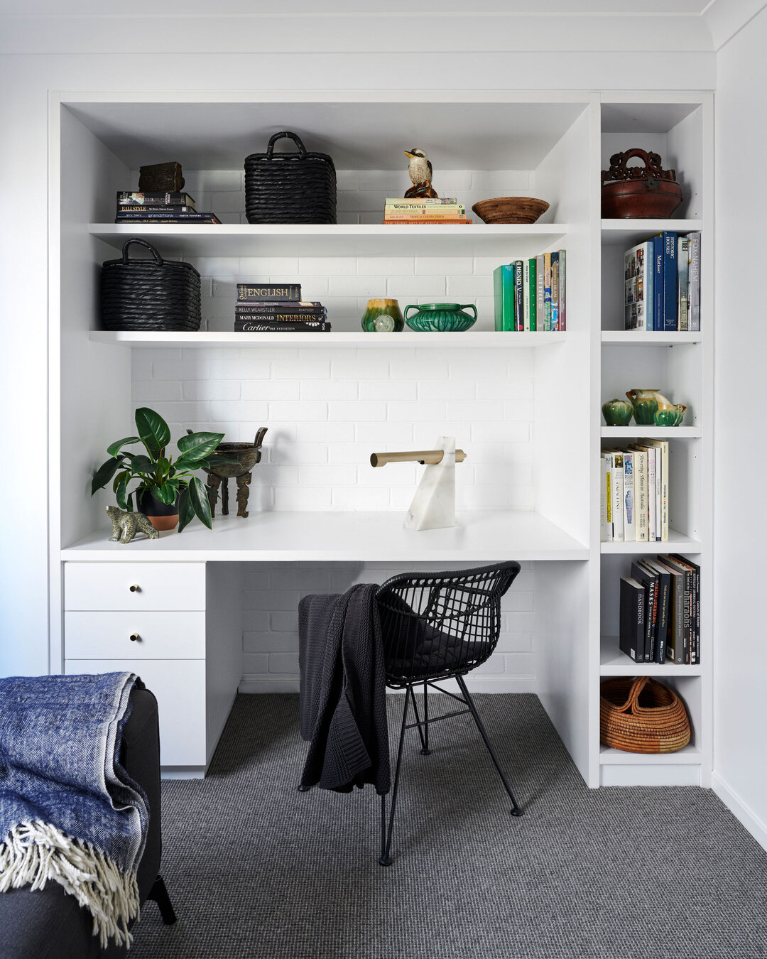 PORT STEPHENS HOUSE I - A deep desk and shelving provide ample workspace, allowing for productivity and organisation. Behind, an exposed painted brick wall adds an industrial yet artistic backdrop. Charcoal wool carpet grounds the space, creating a c