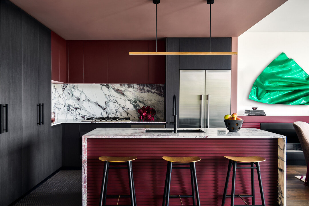 DARLINGHURST APARTMENT - the island bench takes center stage with its dramatically veined burgundy marble, exuding a sense of luxury and drama. Brass counter stools and a matching brass pendant light add a touch of glamour and sophistication. Behind,