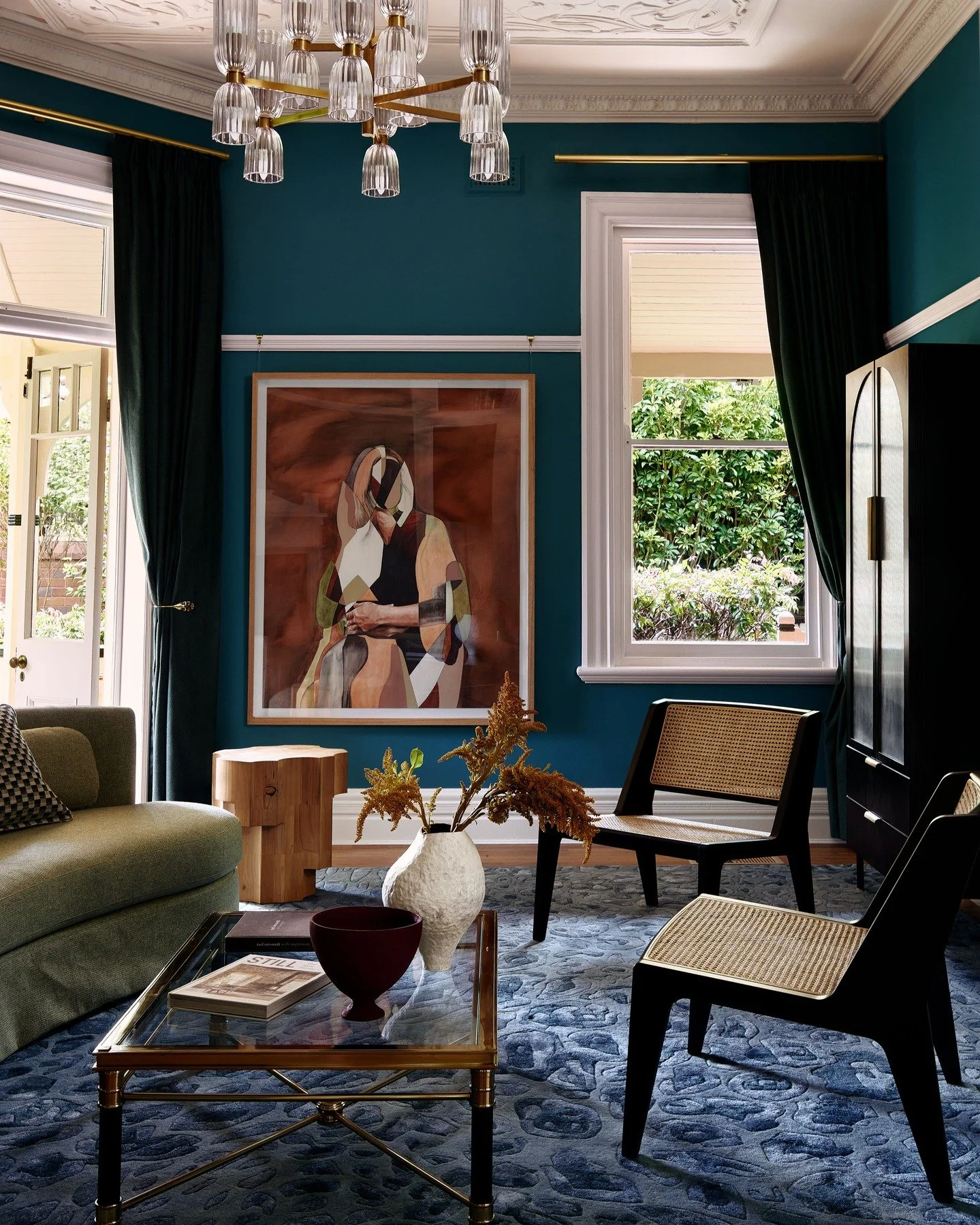 KILLARA HOUSE - Deep blue-green walls envelop the room in richness and poise, creating a striking backdrop for the interplay of texture and form. Ornate plasterwork crowns the ceiling, while velvet drapery, cane chairs and a sculptural timber side ta