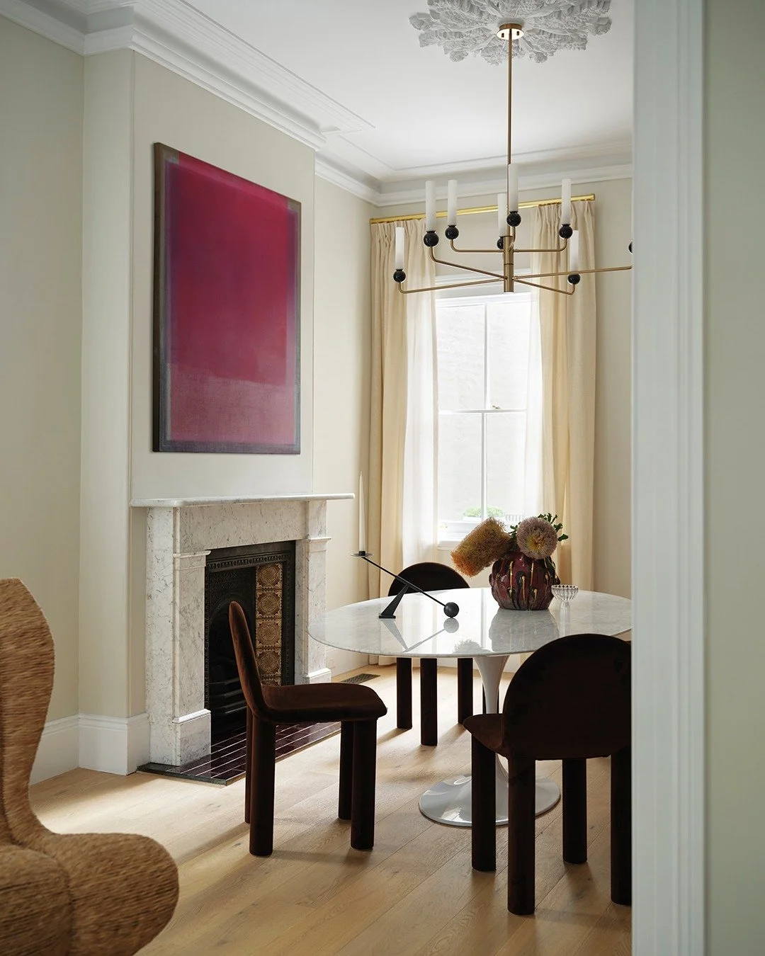CHIPPENDALE TERRACE HOUSE — In the dining room, classic detailing meets contemporary warmth. A marble fireplace and crisp joinery anchor the space, while velvet chairs and a sculptural chandelier echo the home’s play between softness and