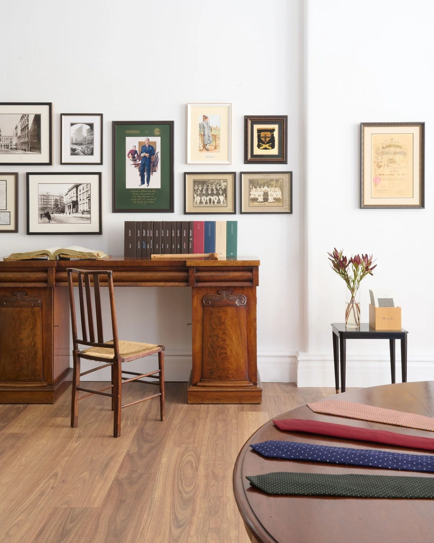 J H CUTLER - An archival wall above a walnut desk, layered with tailoring collectibles and framed history. Pattern books, illustrations and silk ties sit in alignment, where craft and continuity take precedence over display.

Interior Design &amp; De