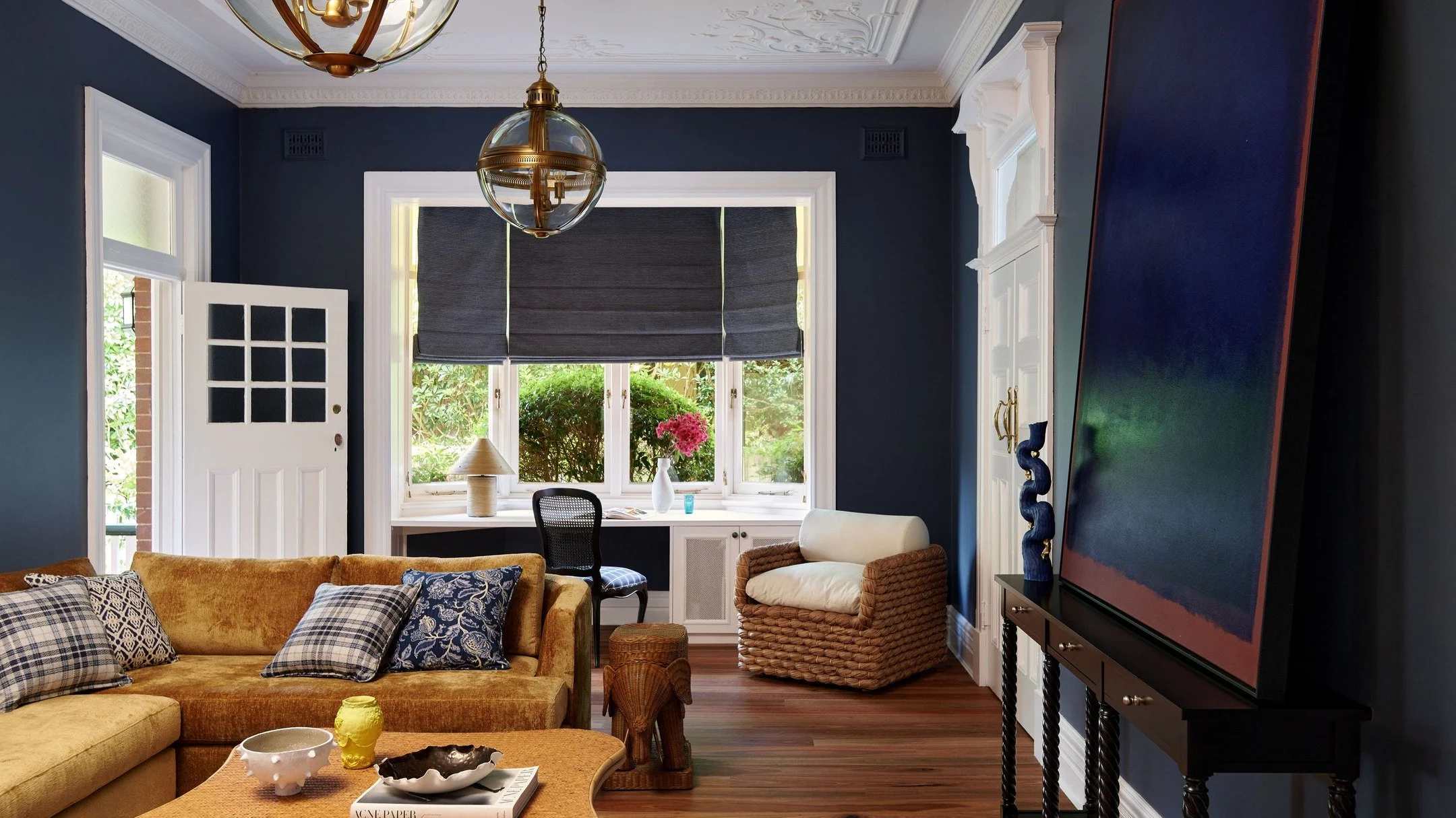 KILLARA HOUSE &mdash; A media room moody with depth and colour. Deep blue walls set the backdrop for layered seating, woven textures and timber underfoot, while sculptural lighting and a large-scale artwork bring focus to the room. A space designed f