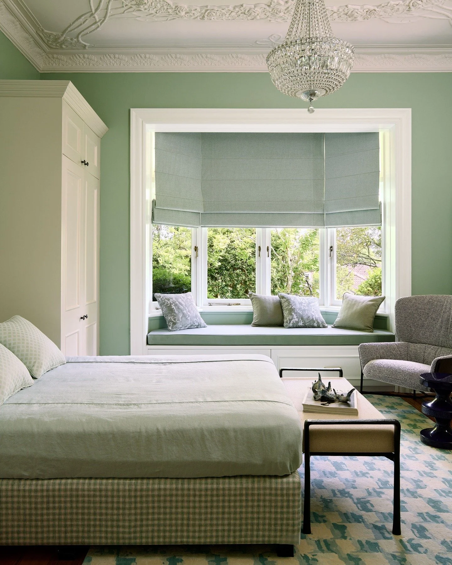 KILLARA HOUSE &mdash; A guest room washed in green, with original plasterwork overhead and an ornate crystal chandelier. A new built-in bay window seat frames the garden view, our tailored approach to upholstery balances pattern with light, air and p