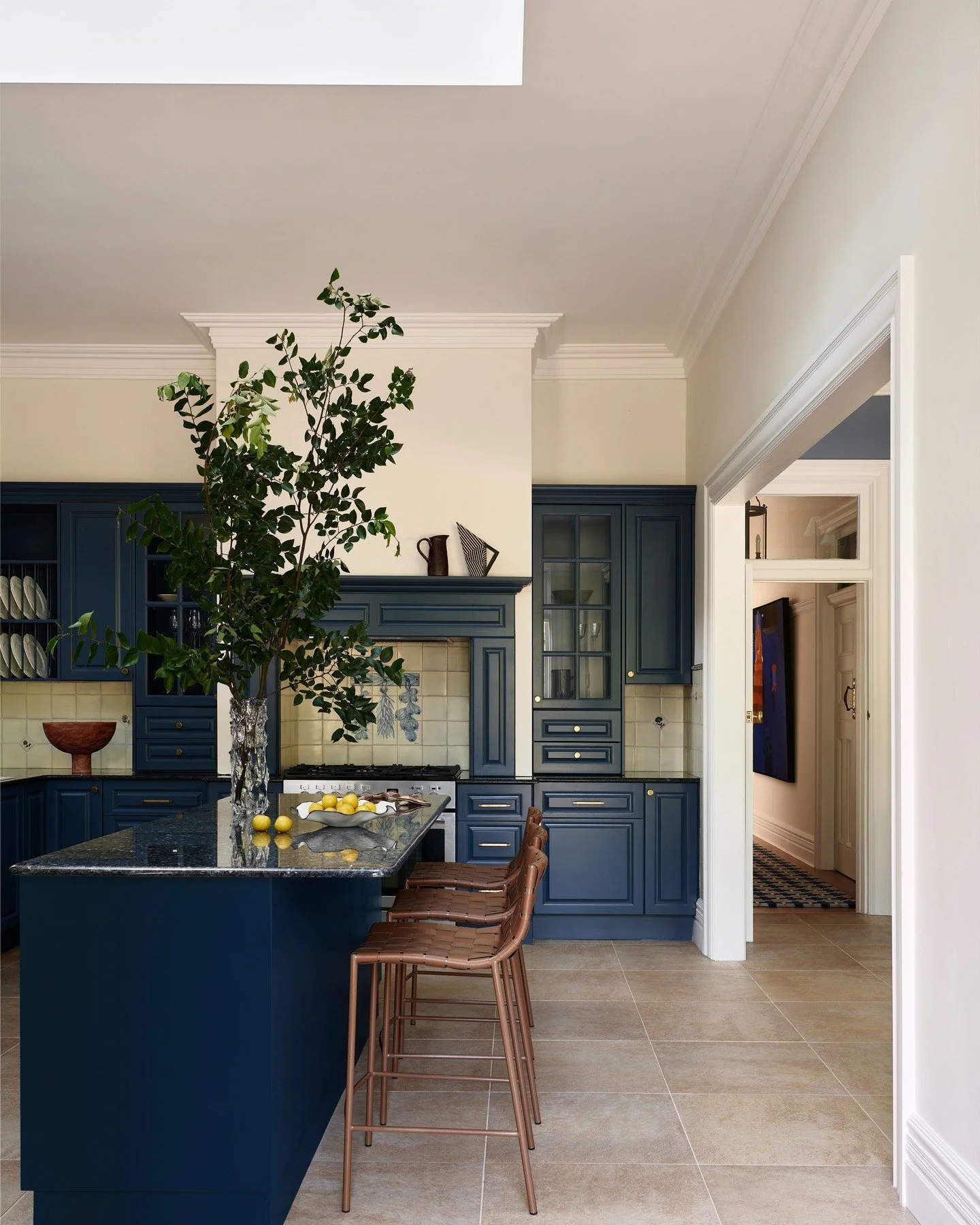 KILLARA HOUSE &mdash; A kitchen anchored by confident blue joinery, a sparkling granite stone benchtop &amp; set under a generous skylight. The original proportions remain legible, while brass hardware, hand-finished tile and leathered seating bring 