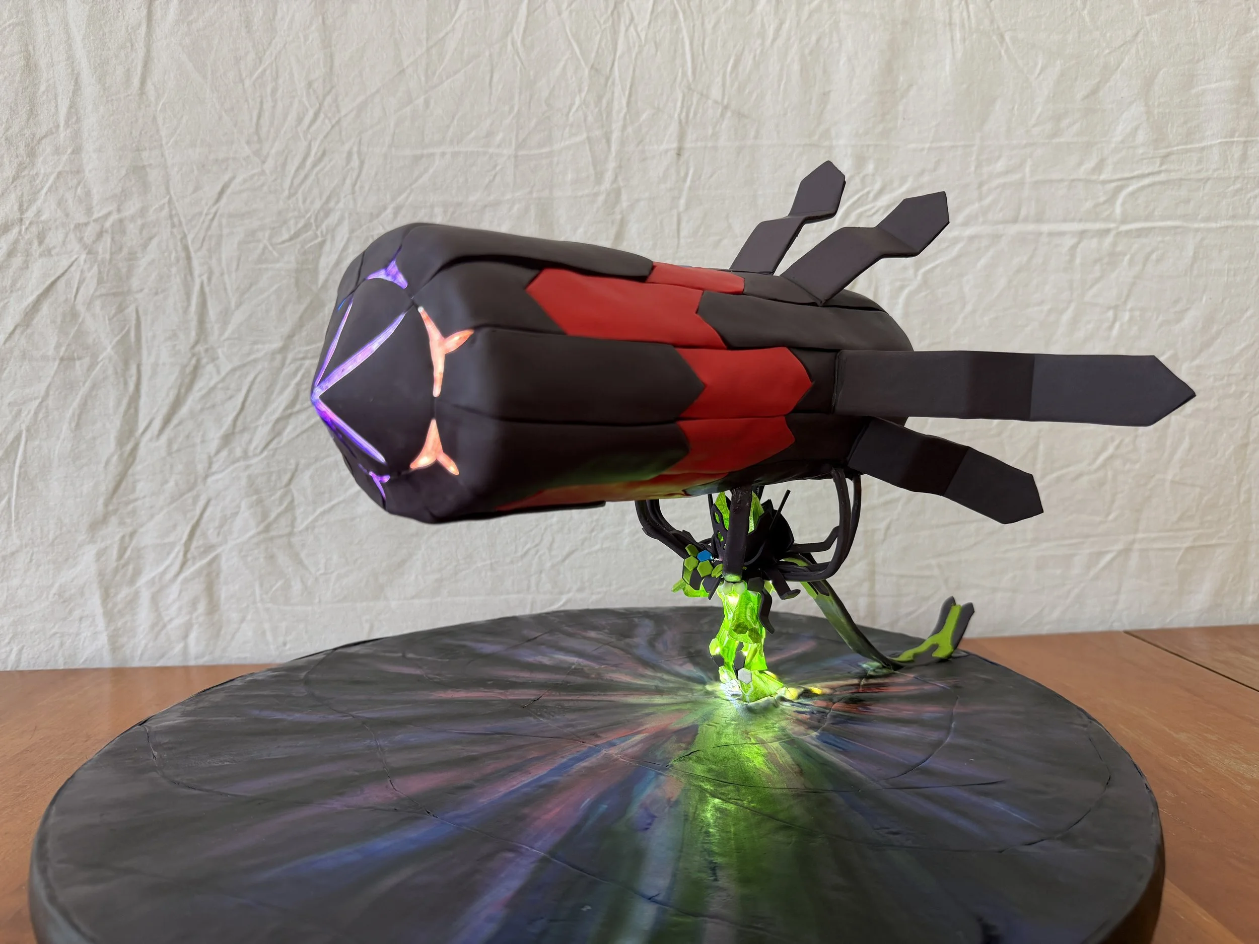 Cake shaped like a big rocket held up by a small glowing green figure with a cape