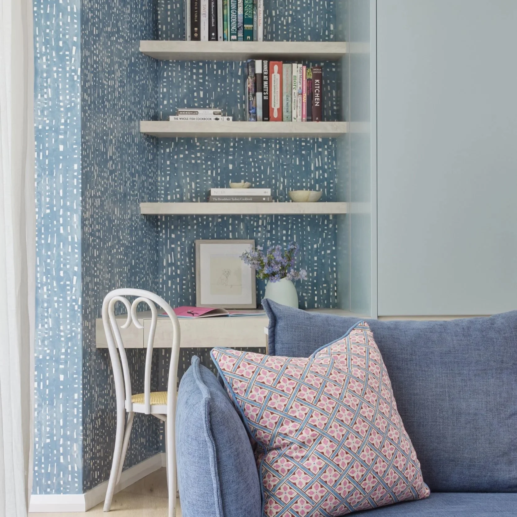 Small built-in desk with floating shelves and blue wallpaper