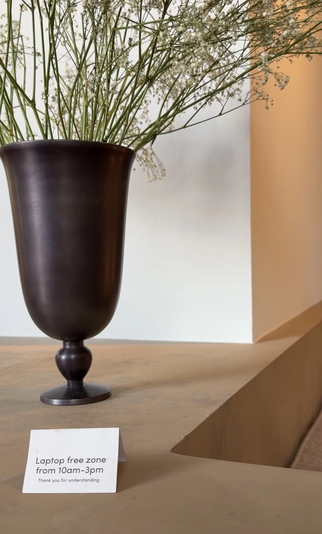 Communal seating area in a cafe with a laptop free sign