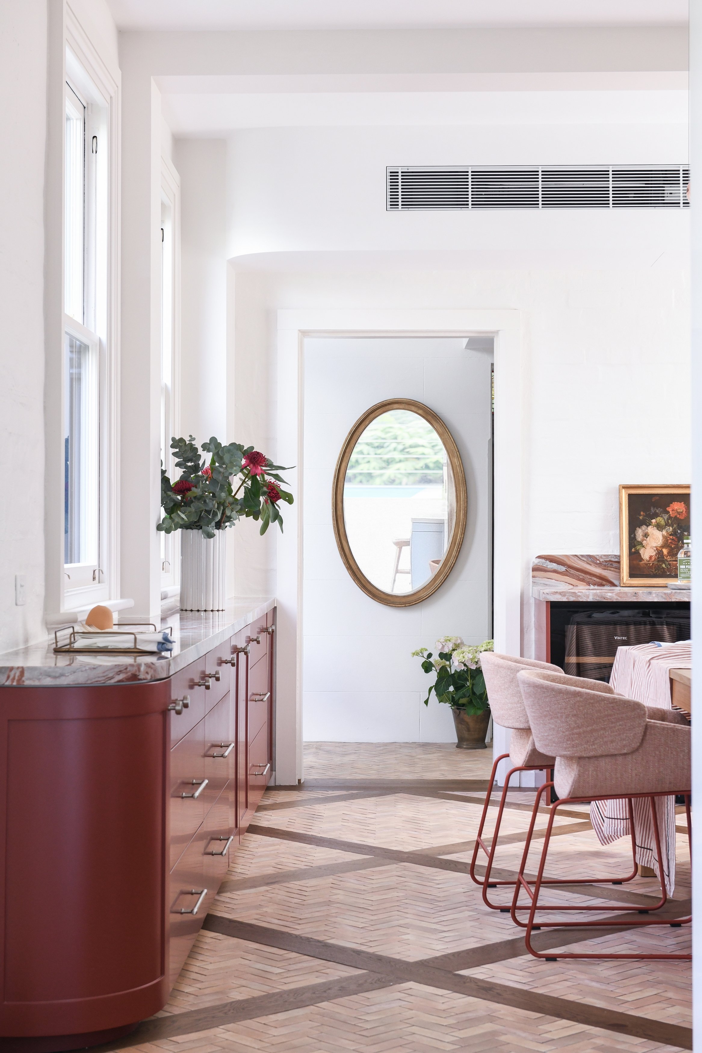 Marble topped burgundy sideboard in dining room with timber and terracotta flooring
