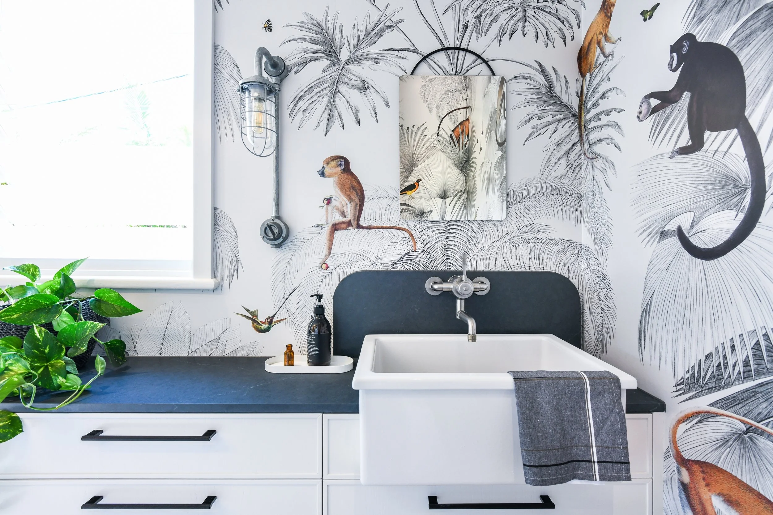 Fun laundry room with industrial style sink and monkey wallapaper