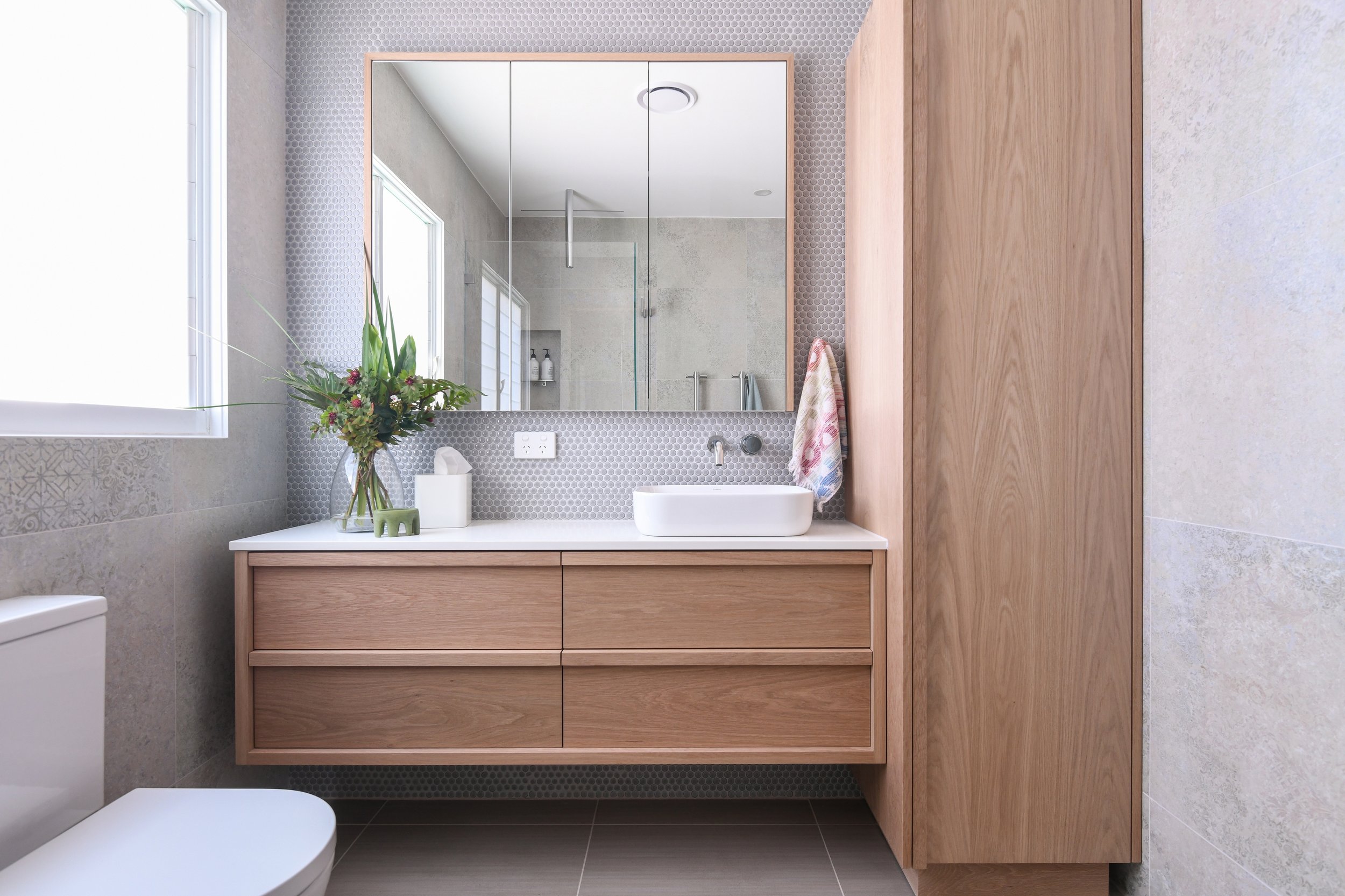 A spacious bathroom with oak vanity with ample storage, shaving cabinet and penny tiles