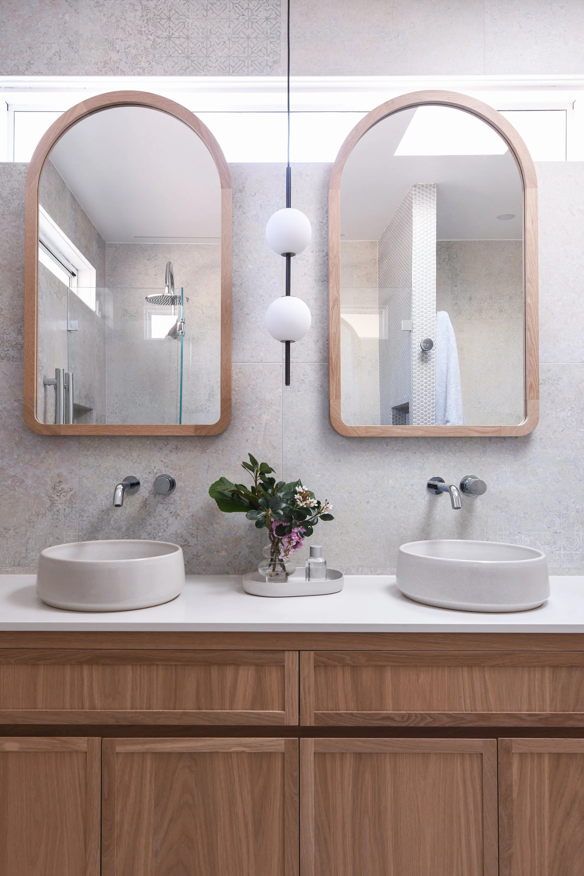 A bright ensuite with oak double vanity and shaving cabinets