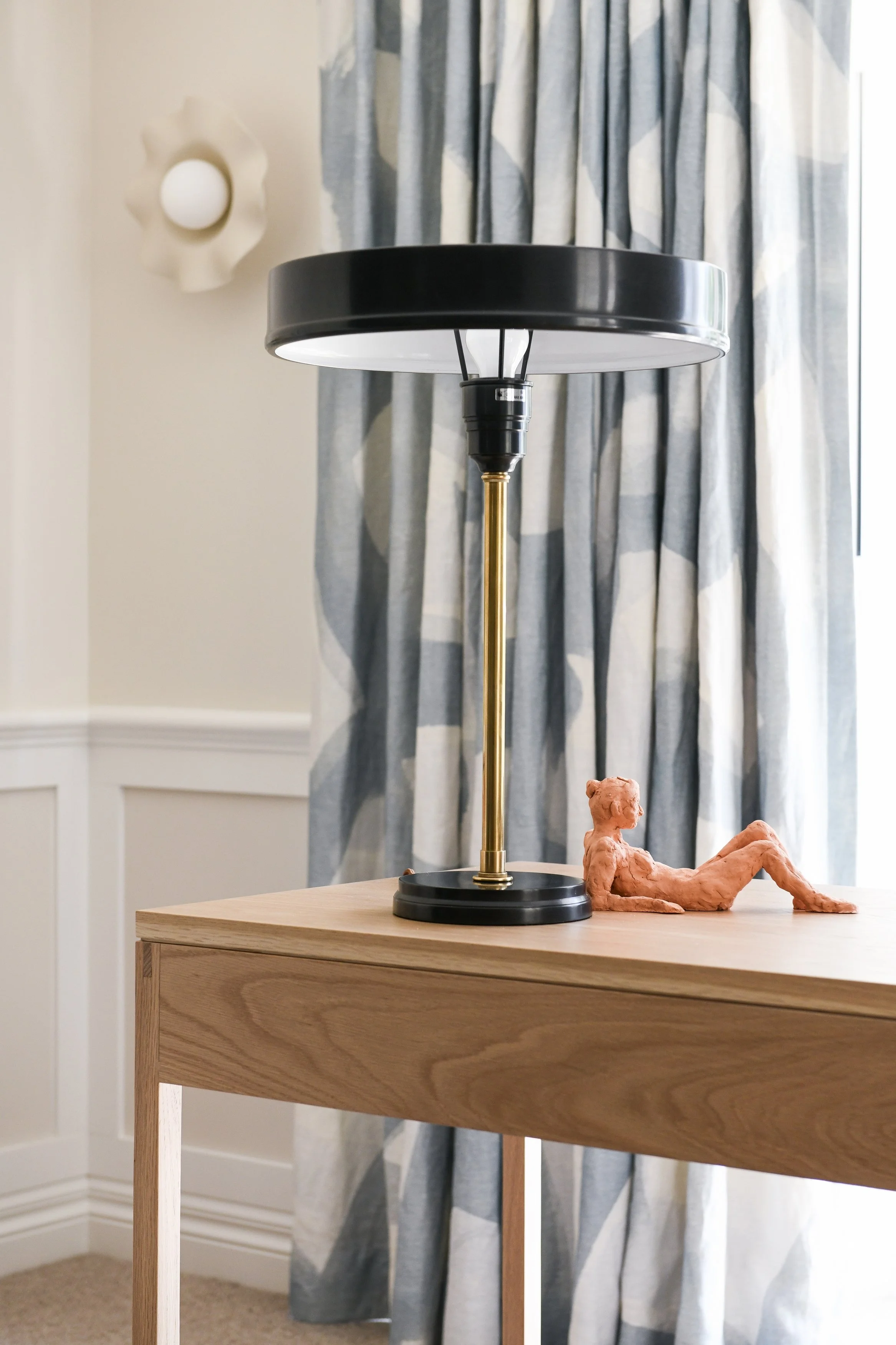 Home office desk with midcentury lamp and full length drapes behind
