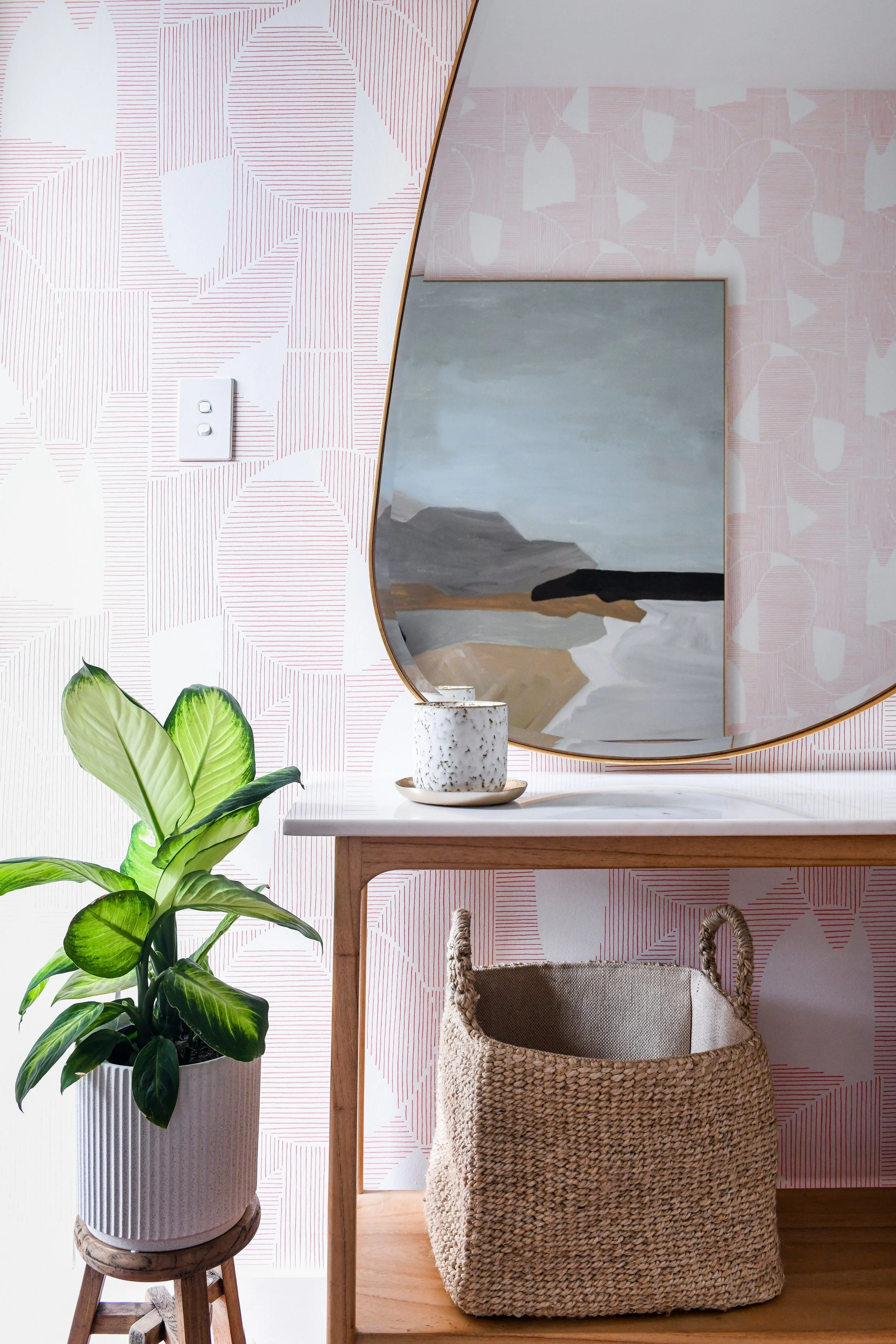 Seaforth entry with pink graphic wallpaper, marble hall stand, organically shaped mirror and art