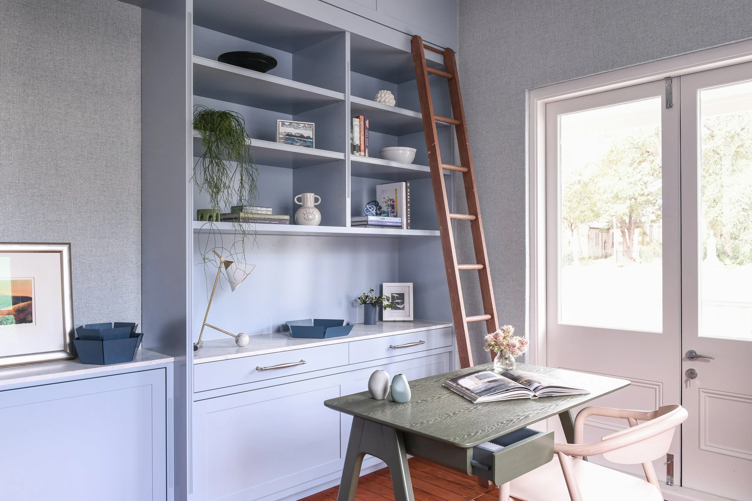 Home office with green timber desk with blue bookcase