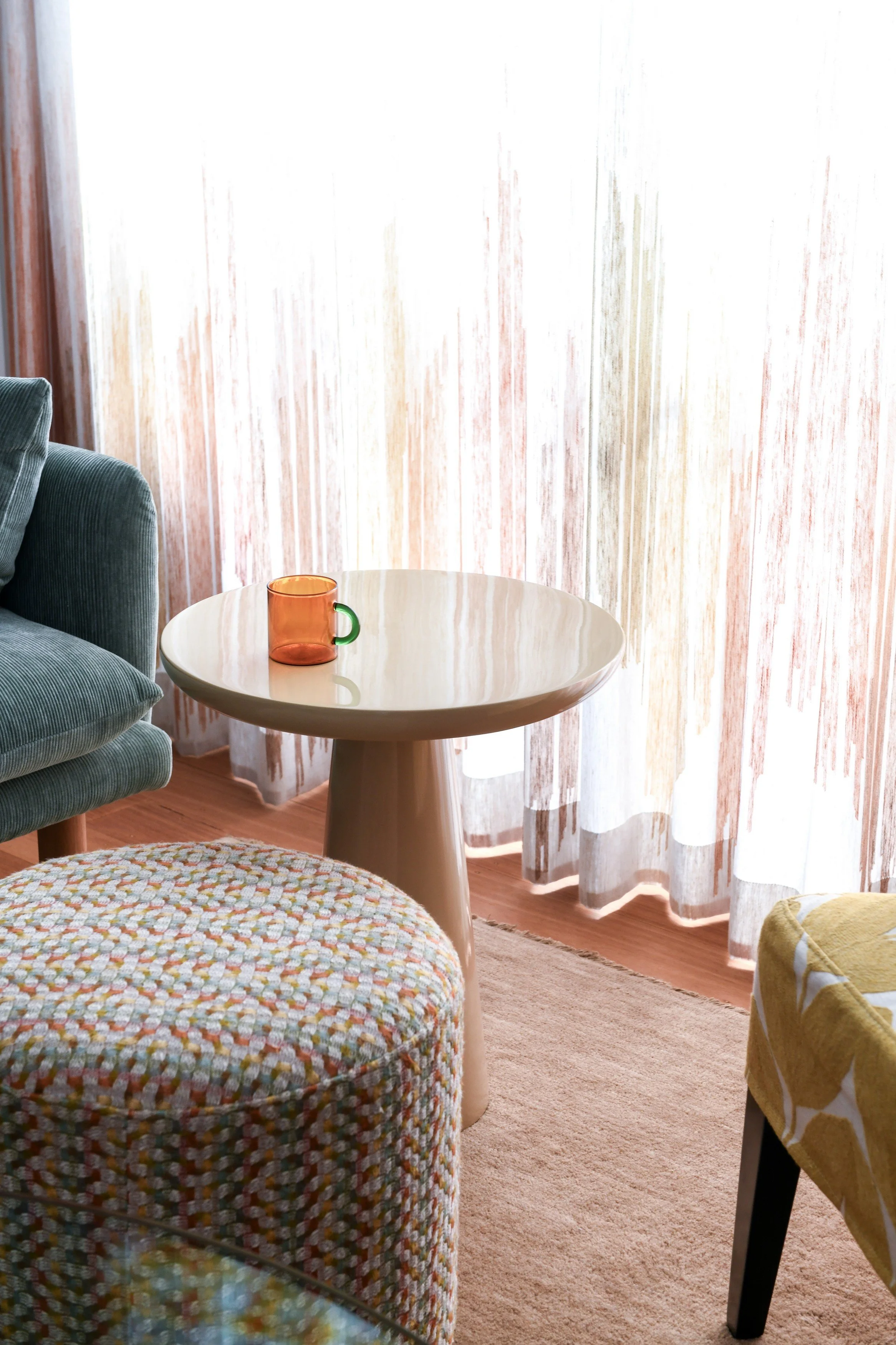 Colourful seating area with plush rug, sheer curtains, and seating in tactile fabrics