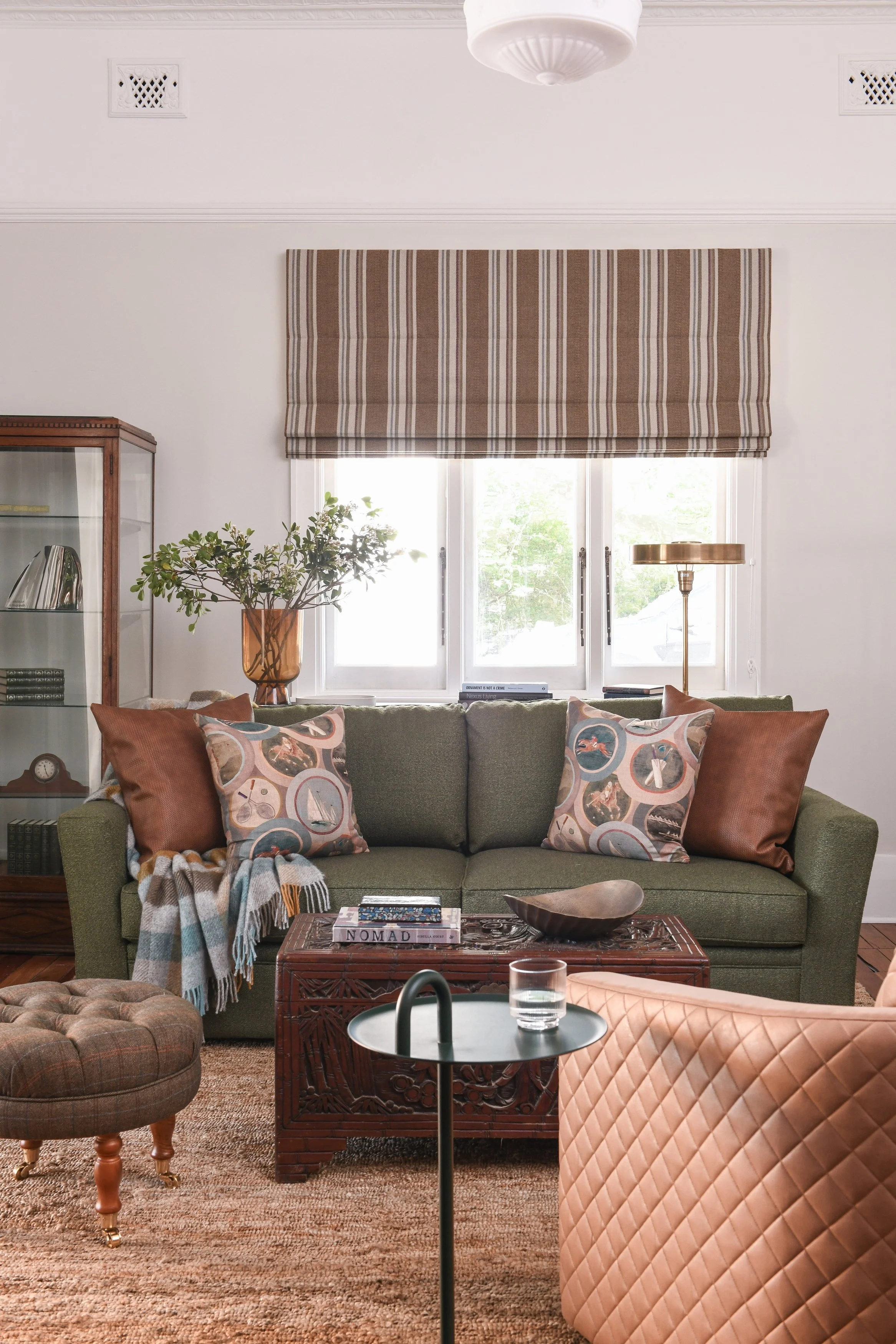 Classic lounge room in green hues with saddle leather and a mix of contemporary and antique furniture